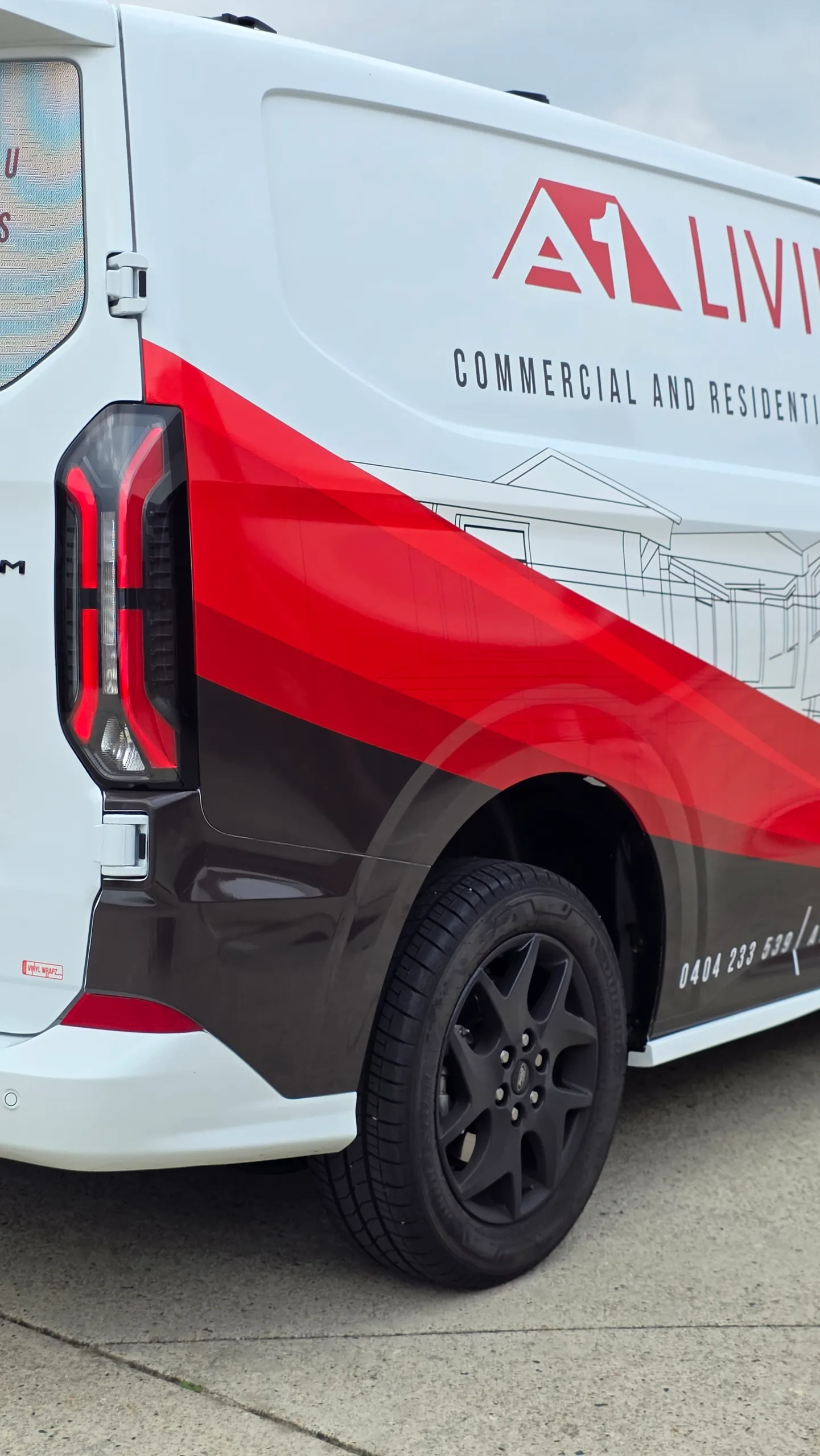 Red and black A1 Living graphics above the Ford Transit Custom rear wheel