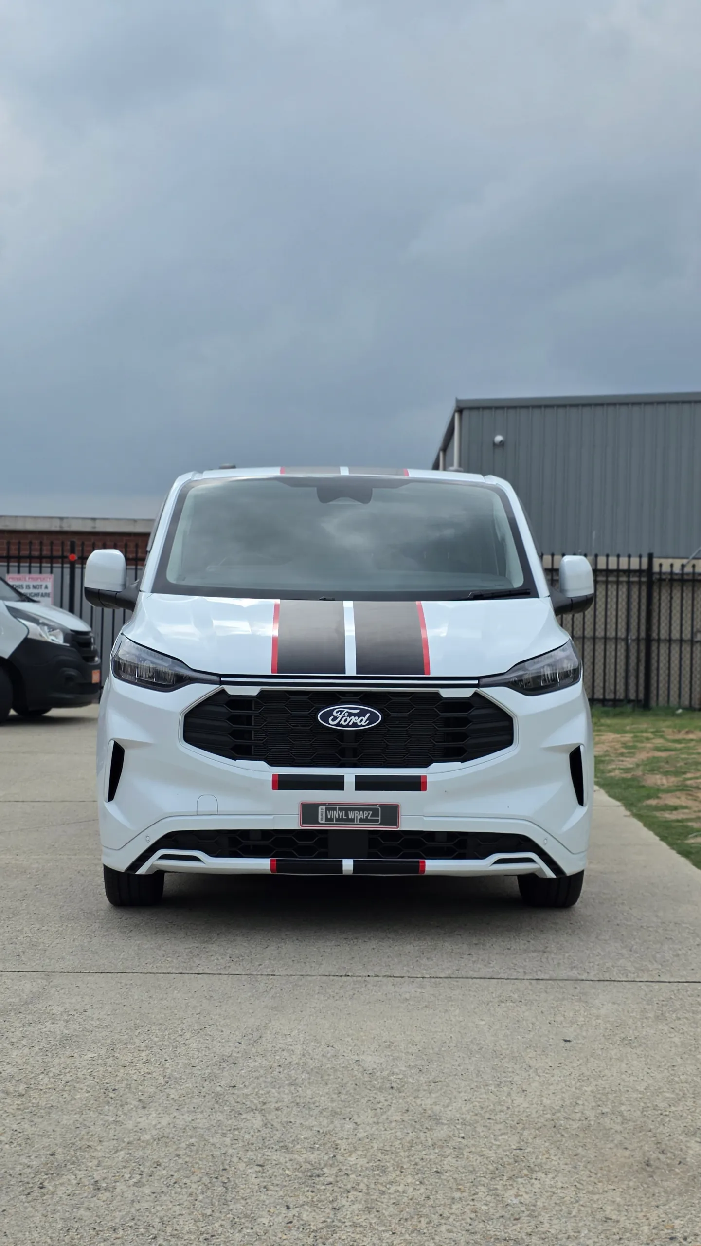 Front view of the white Ford Transit Custom with black stripes edged in red