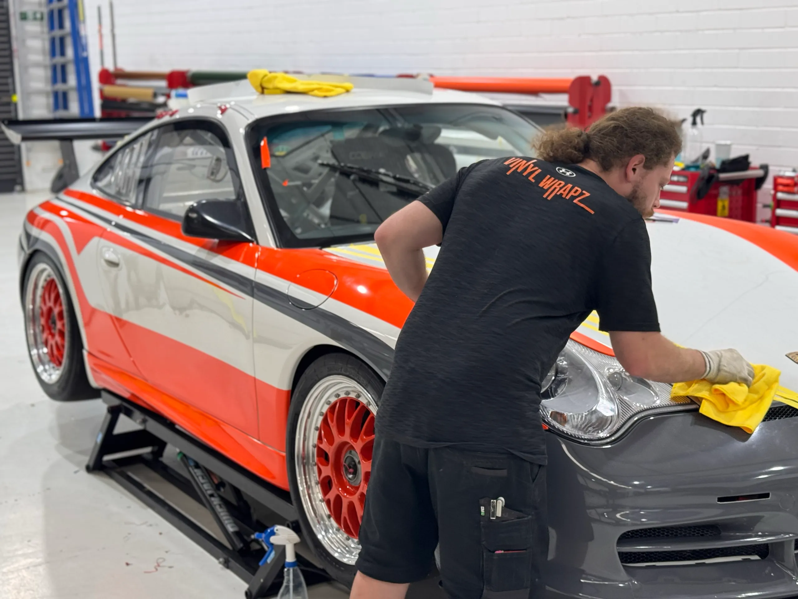 Installer working on the Porsche front end during orange, white and grey graphics installation