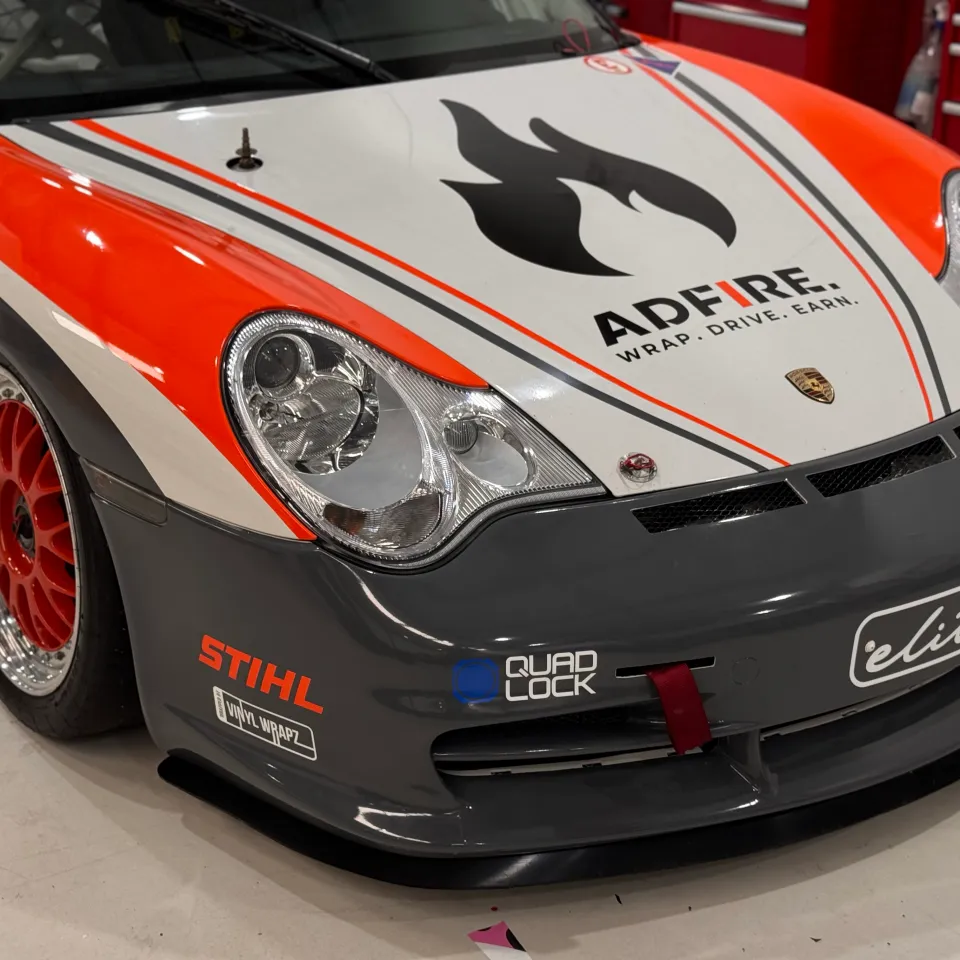 Adfire flame logo on the Porsche bonnet above a grey front bumper and orange wheels