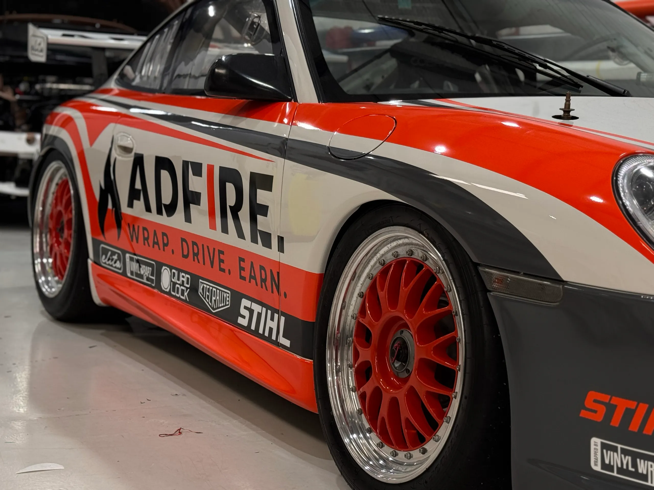 Adfire lettering across the Porsche door with orange and grey stripes