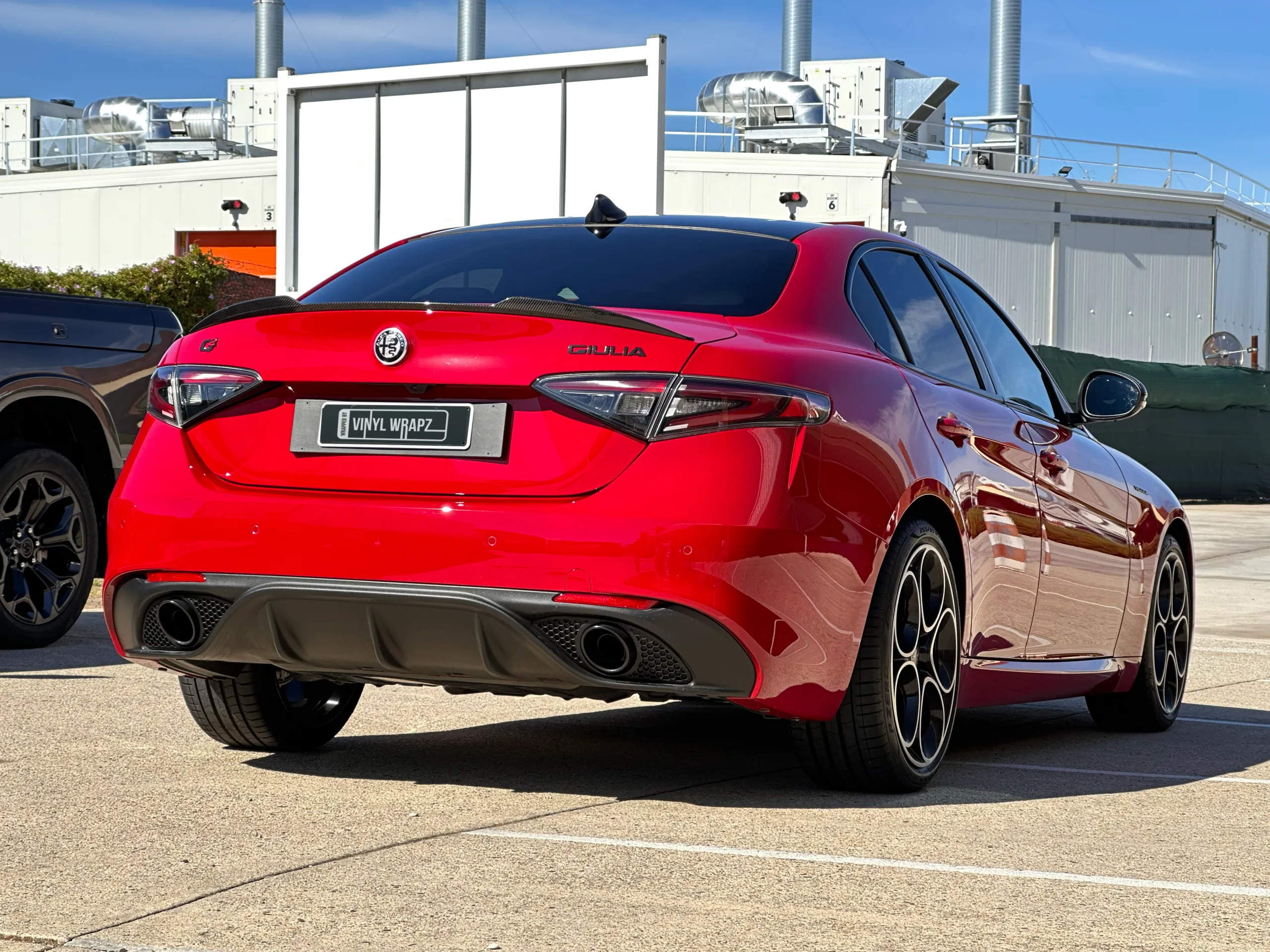 Gloss red Alfa Romeo Giulia viewed from the rear quarter outdoors