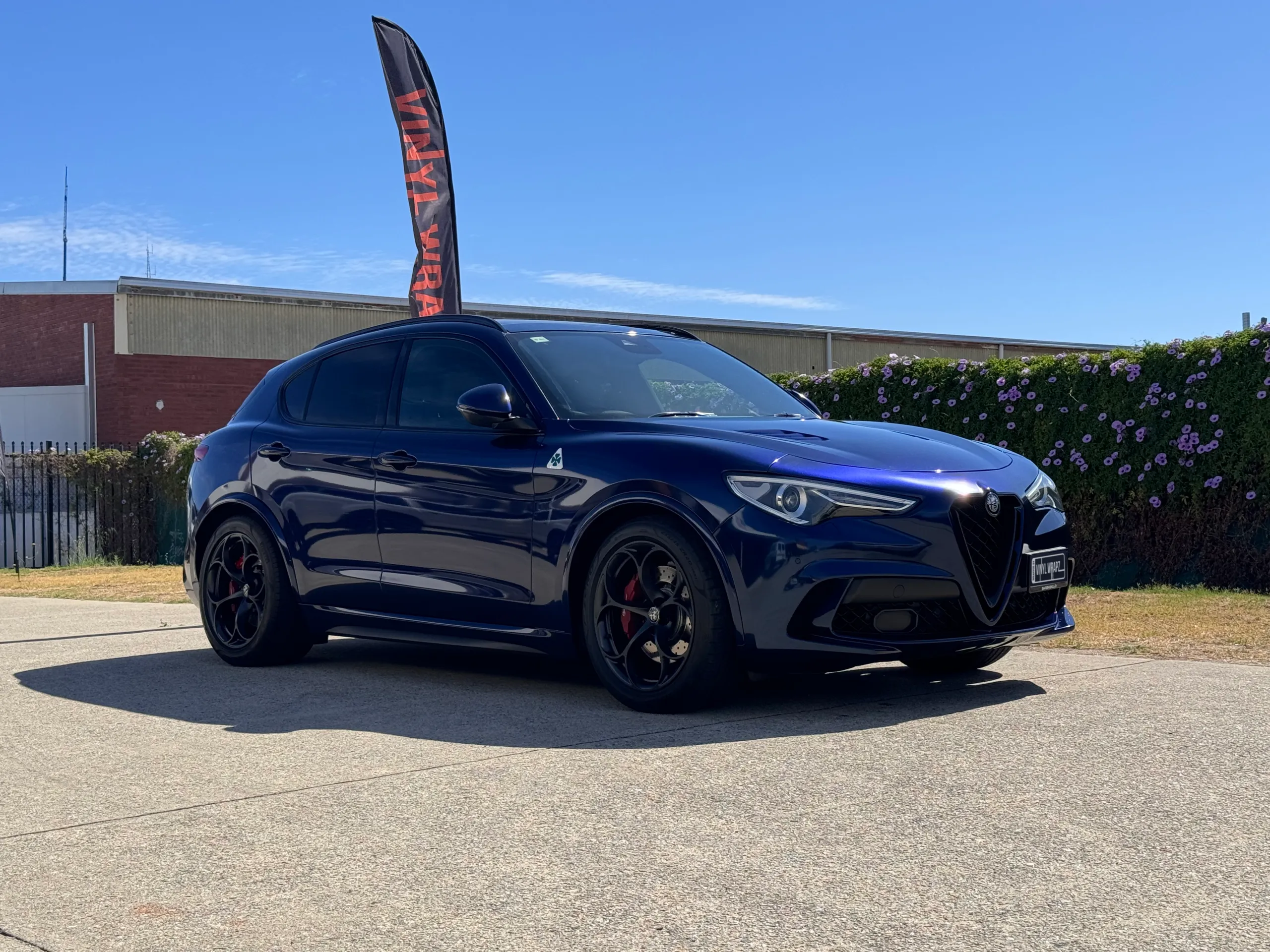 Gloss blue-black Alfa Romeo Stelvio viewed from the front quarter outside the workshop