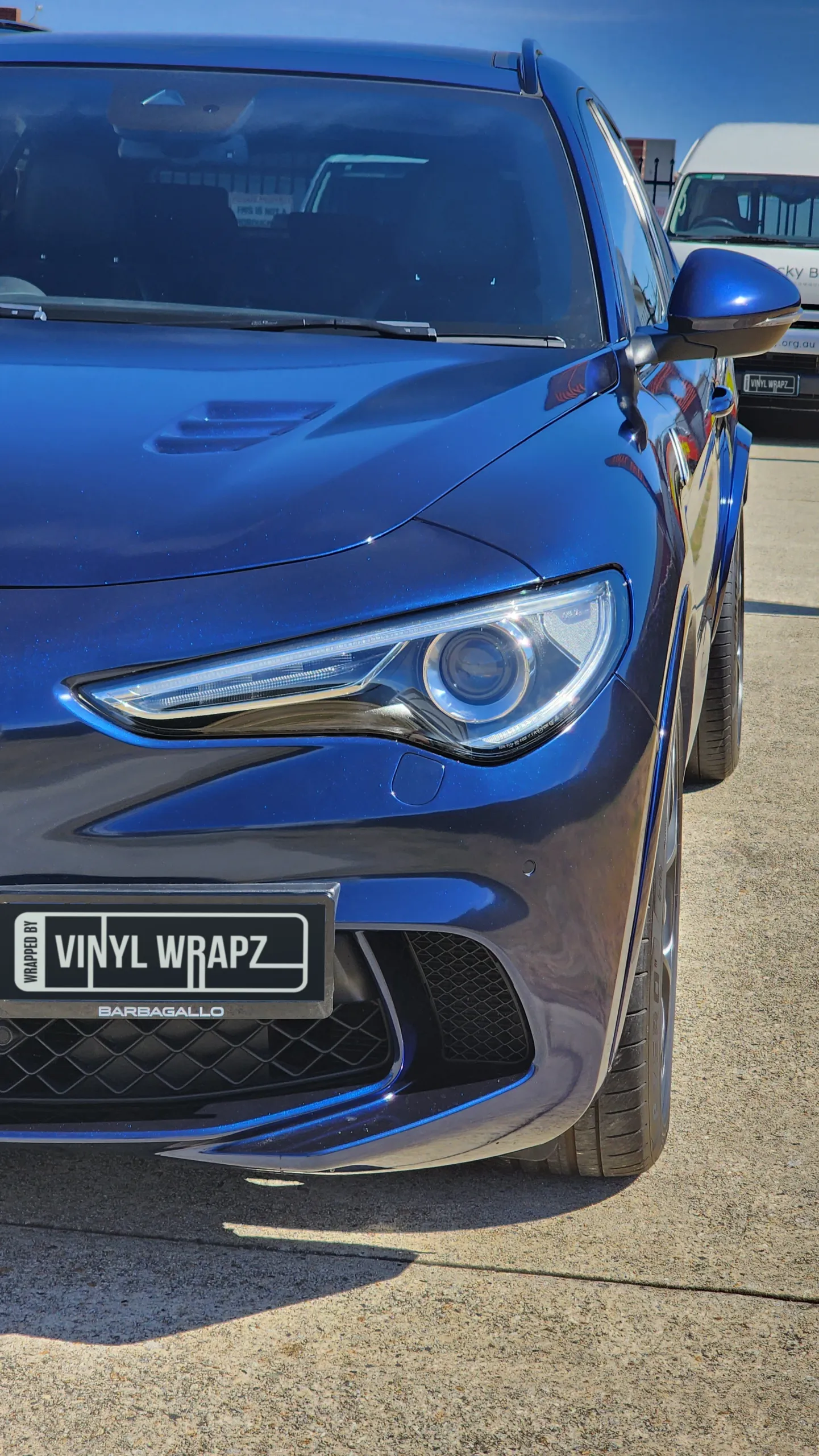 Close-up of the Alfa Romeo Stelvio headlight, blue bonnet and front bumper