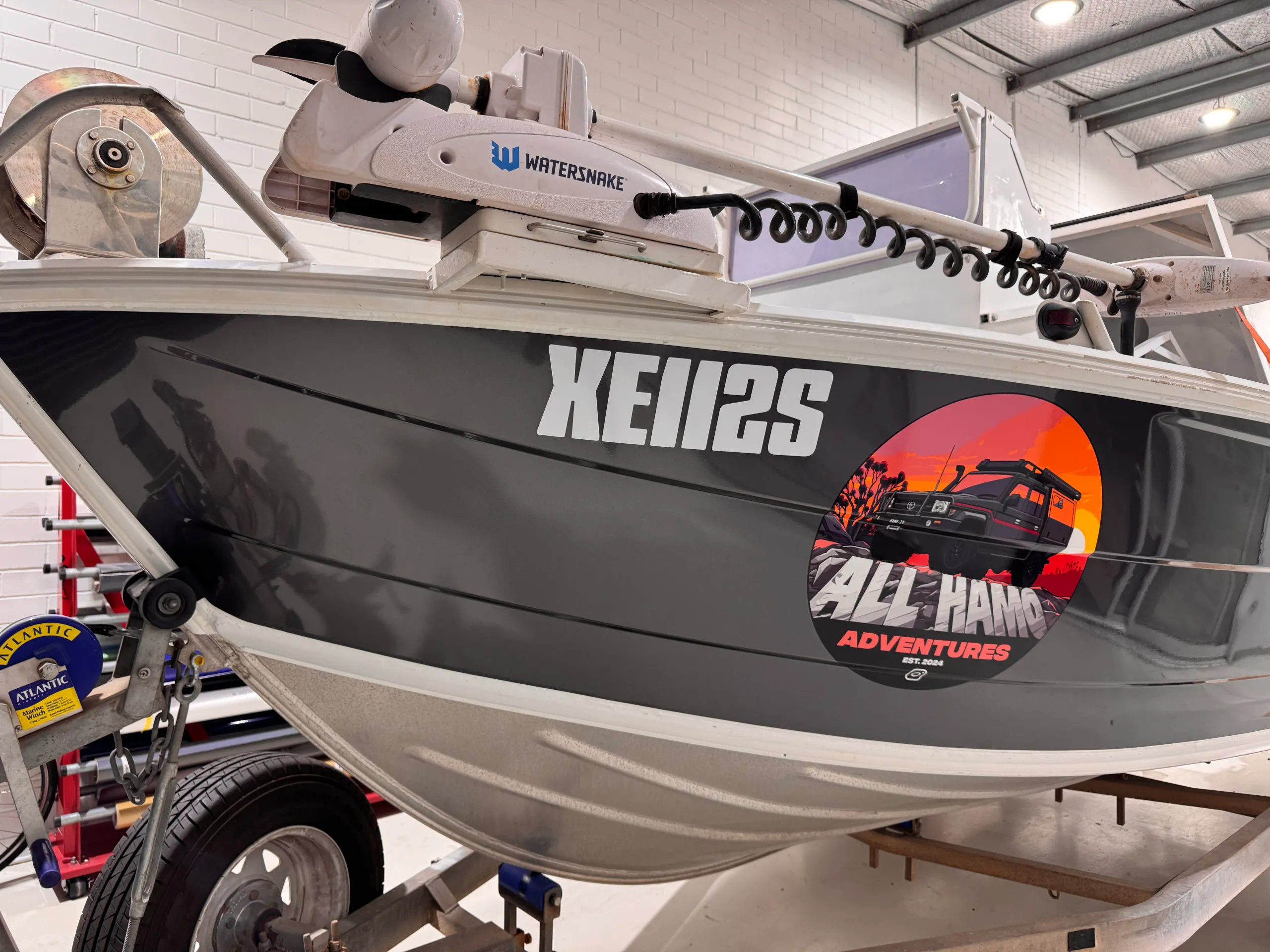 All Hamo Adventures circular logo on the charcoal-grey John Boy boat bow in the workshop