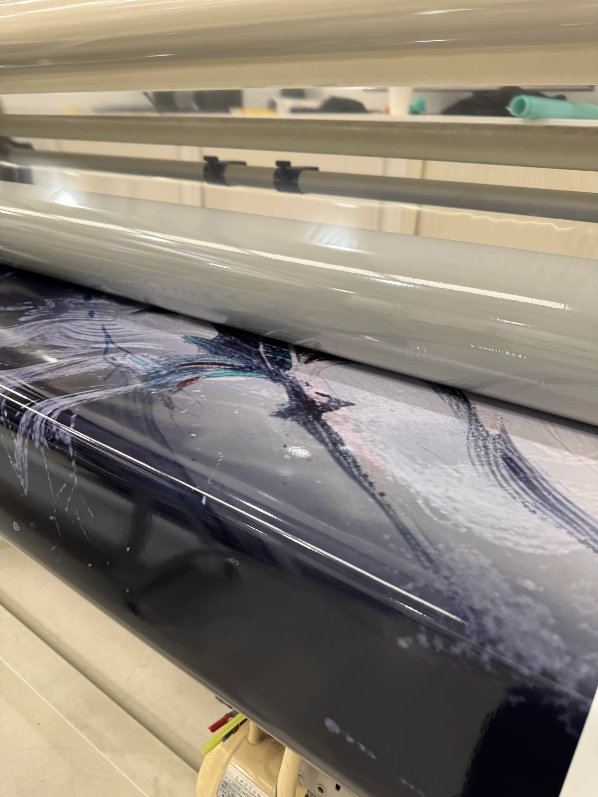 Printed Poseidon boat-wrap artwork passing through a wide-format finishing machine