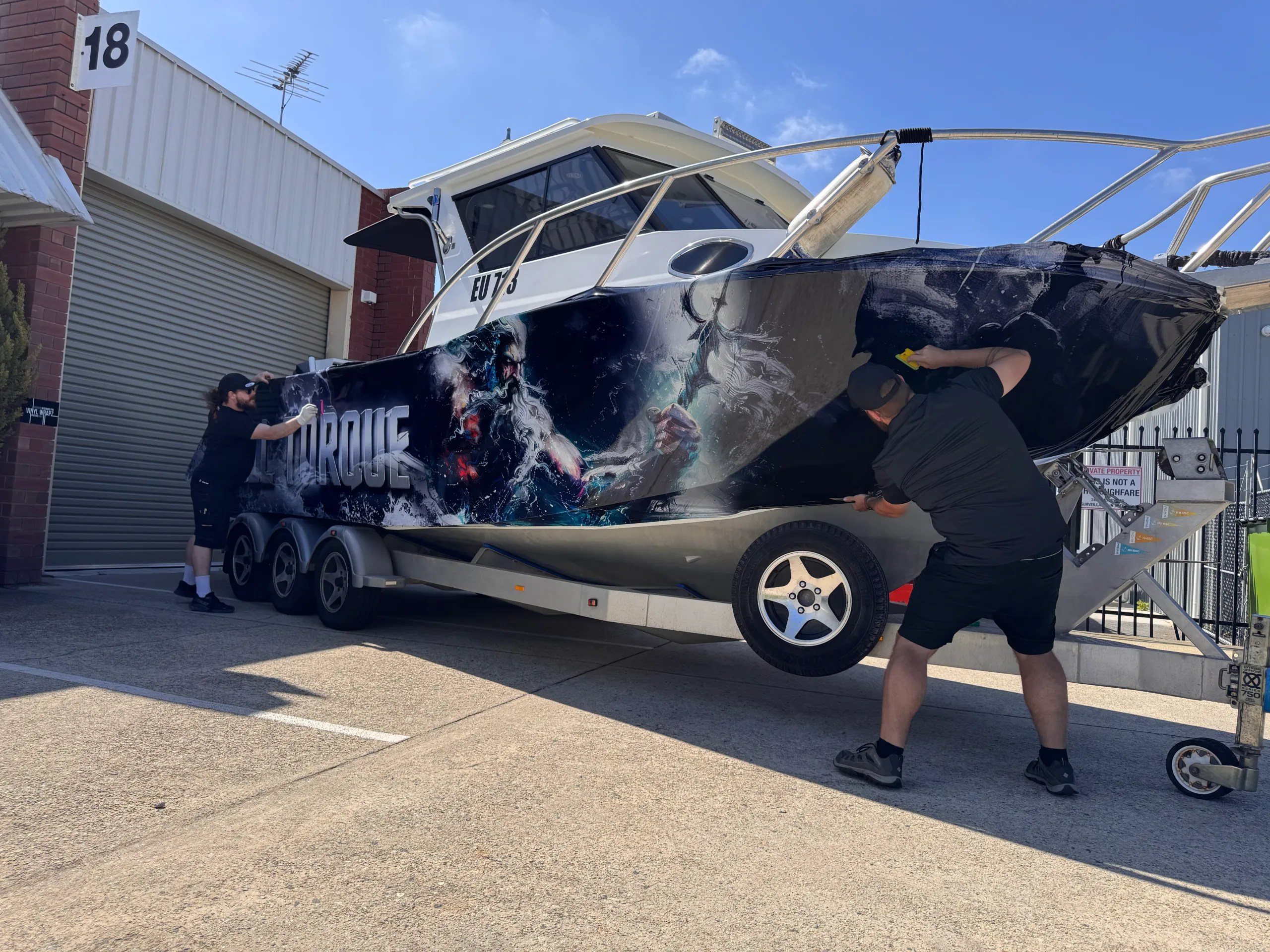 Installers fitting dark blue Poseidon graphics around the Razerline Olympian hull