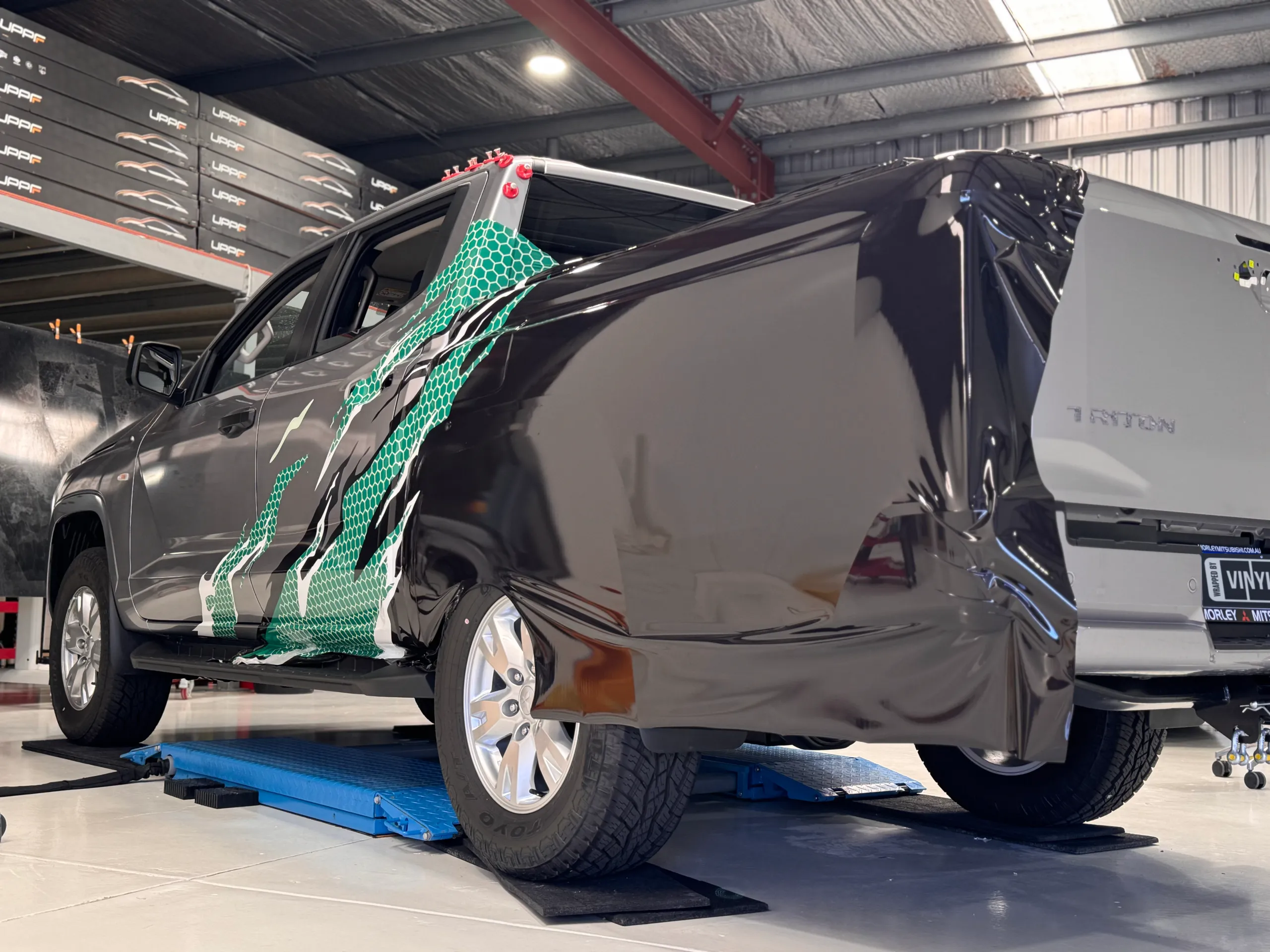 Black and green printed film partly fitted over the Mitsubishi Triton tray side