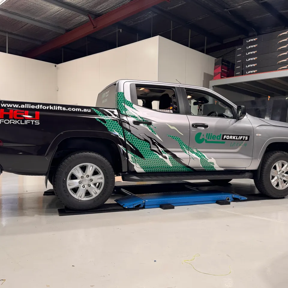 Silver Mitsubishi Triton with black and green Allied Forklifts graphics in the workshop