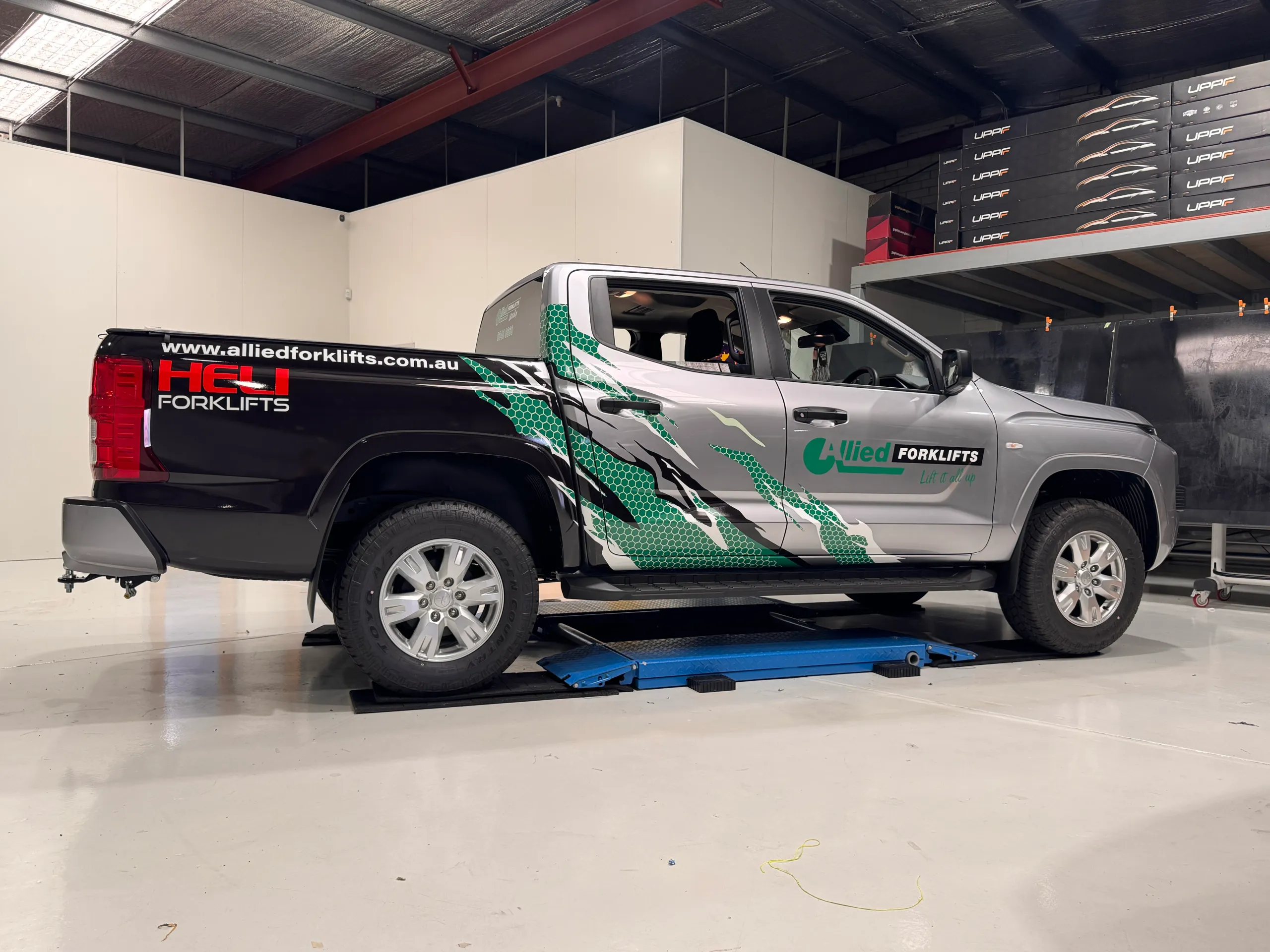 Silver Mitsubishi Triton with black and green Allied Forklifts graphics in the workshop