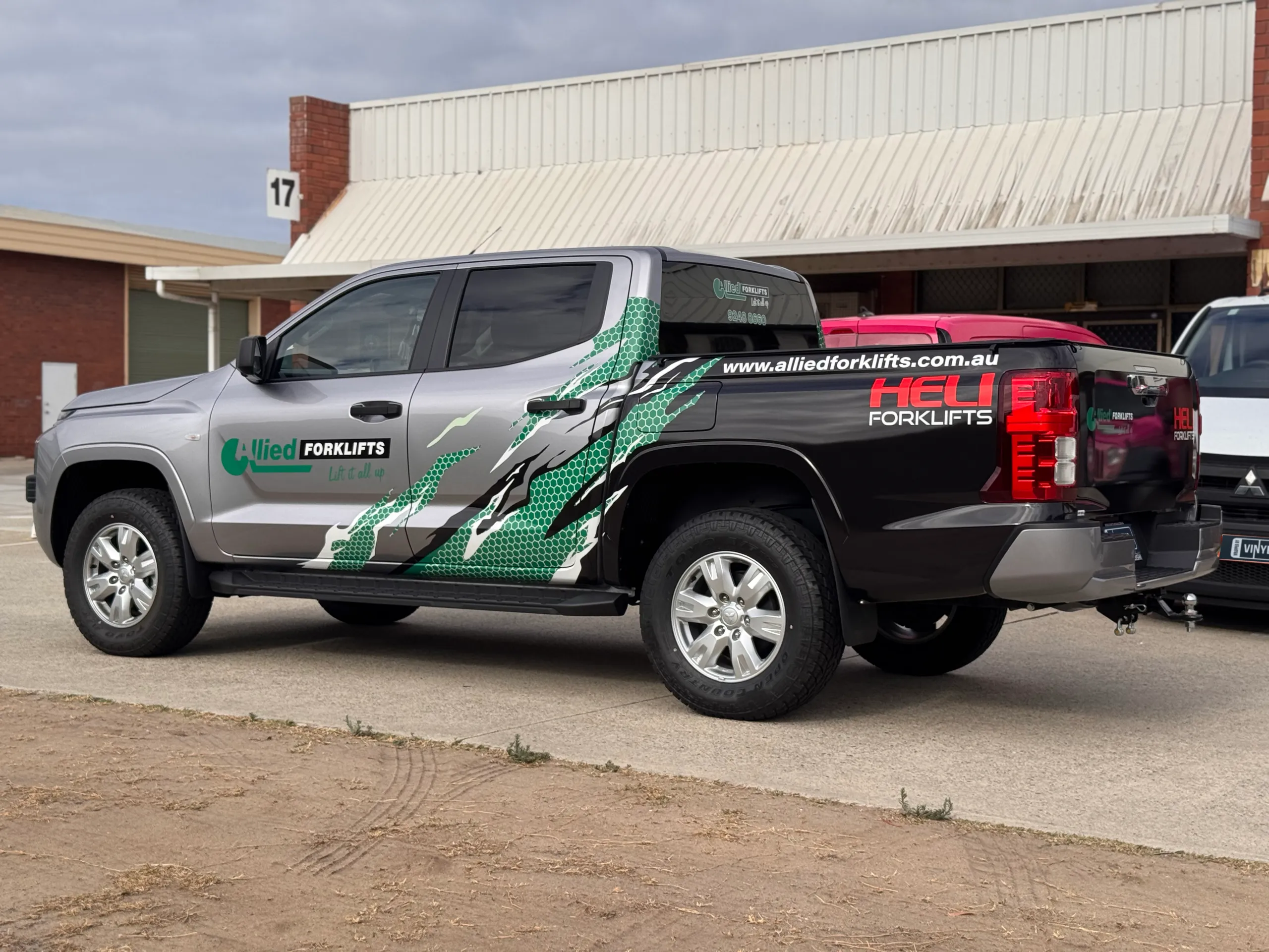 Silver Triton with green honeycomb and white claw graphics outside the workshop