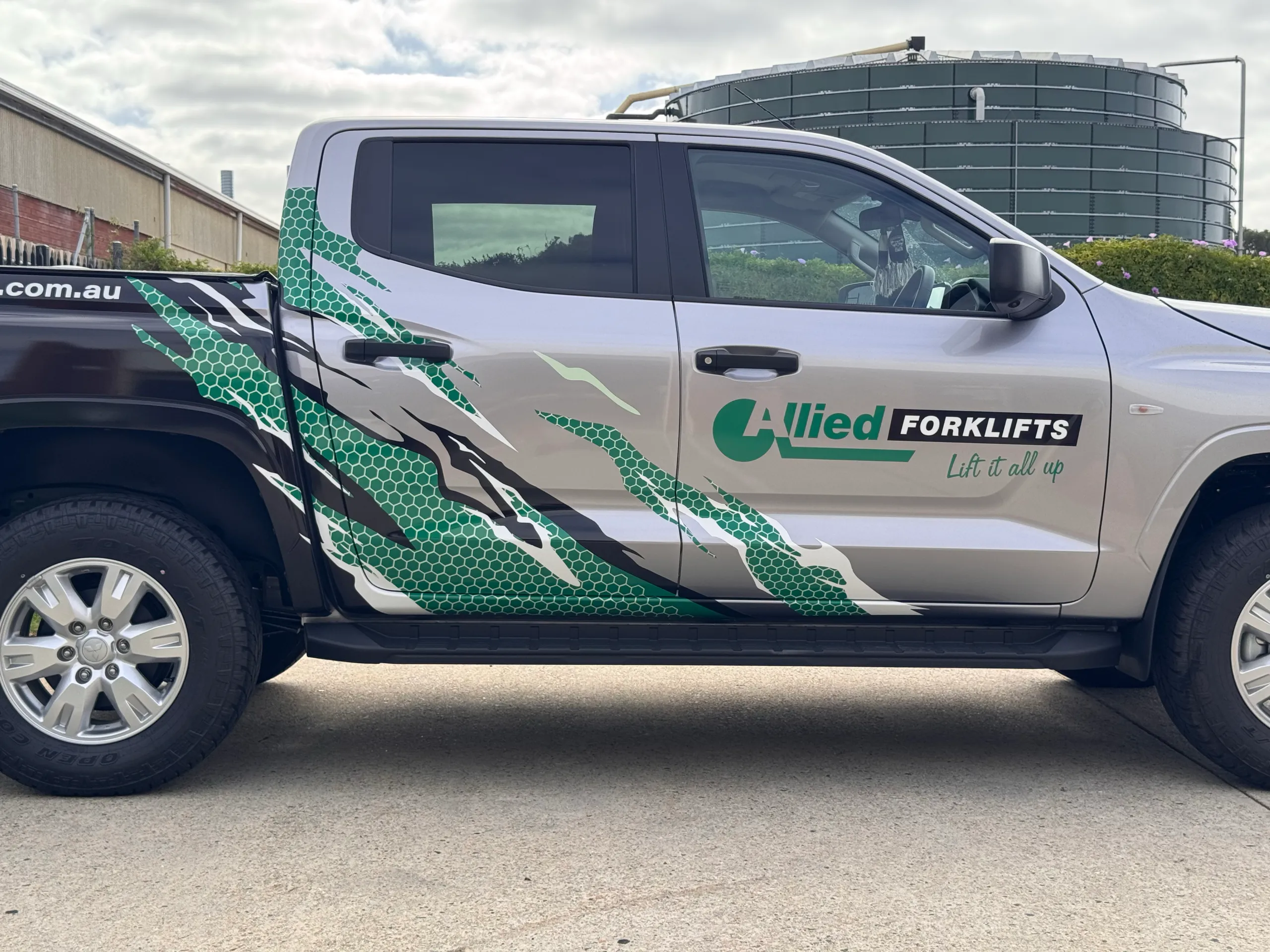Allied Forklifts door logo and green honeycomb graphics on the silver Triton cab