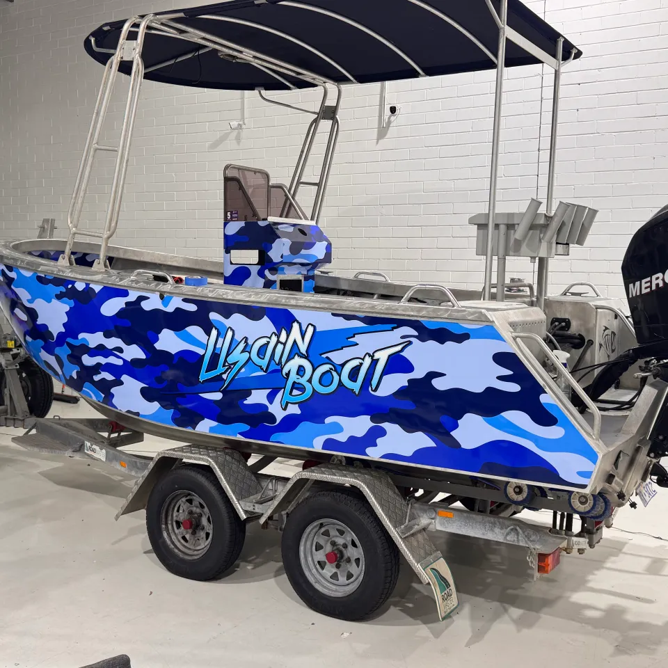 Aluminium centre-console boat with blue camouflage graphics and a Mercury outboard in the workshop