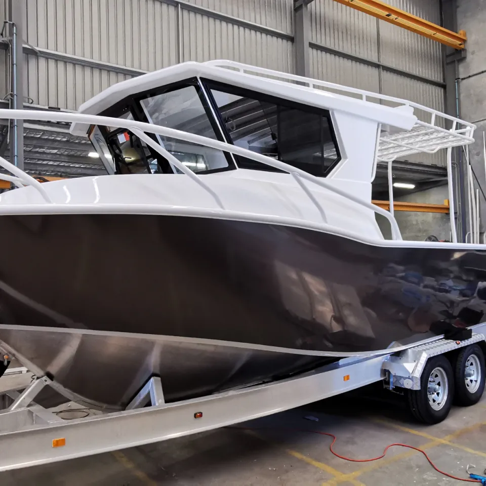 Charcoal aluminium boat with a white cabin on its trailer inside the workshop