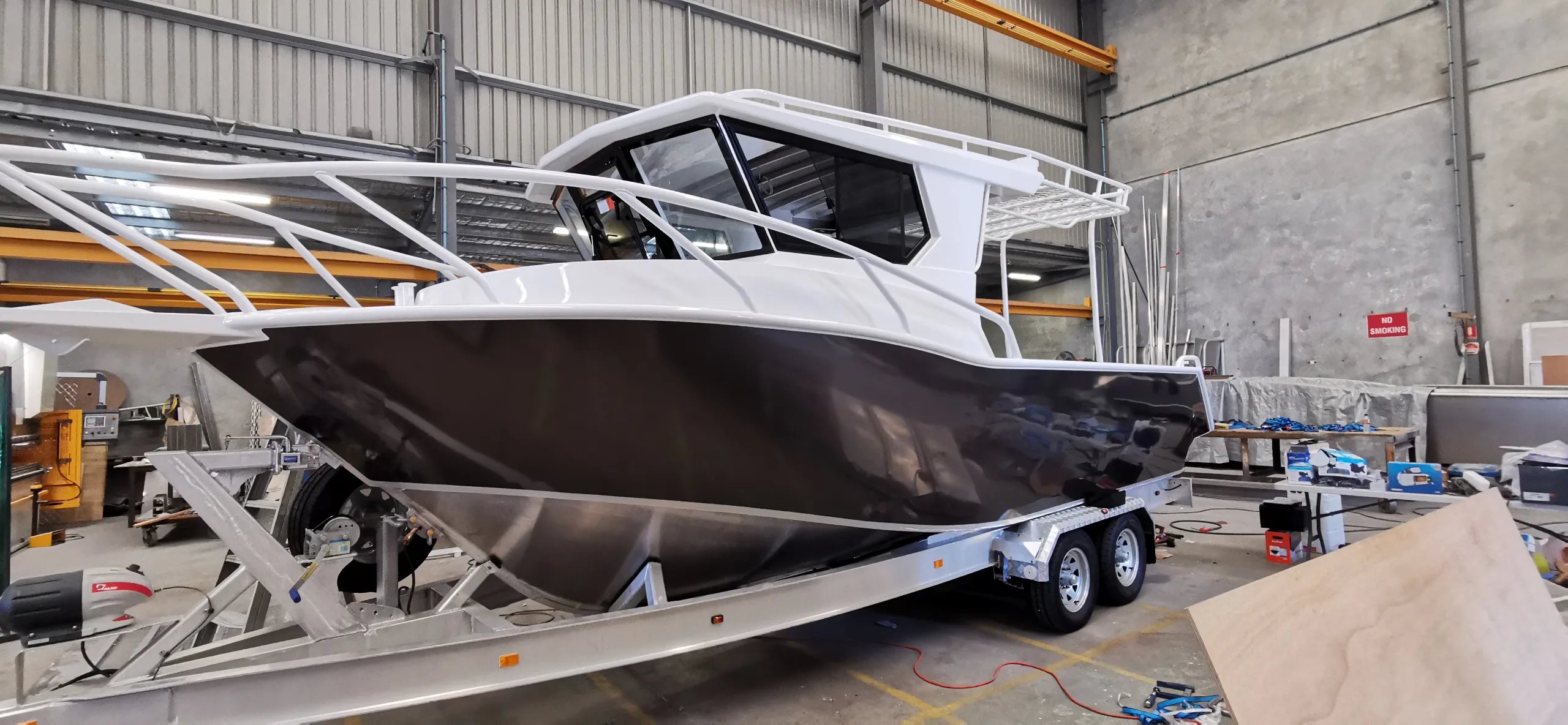 Charcoal aluminium boat with a white cabin on its trailer inside the workshop