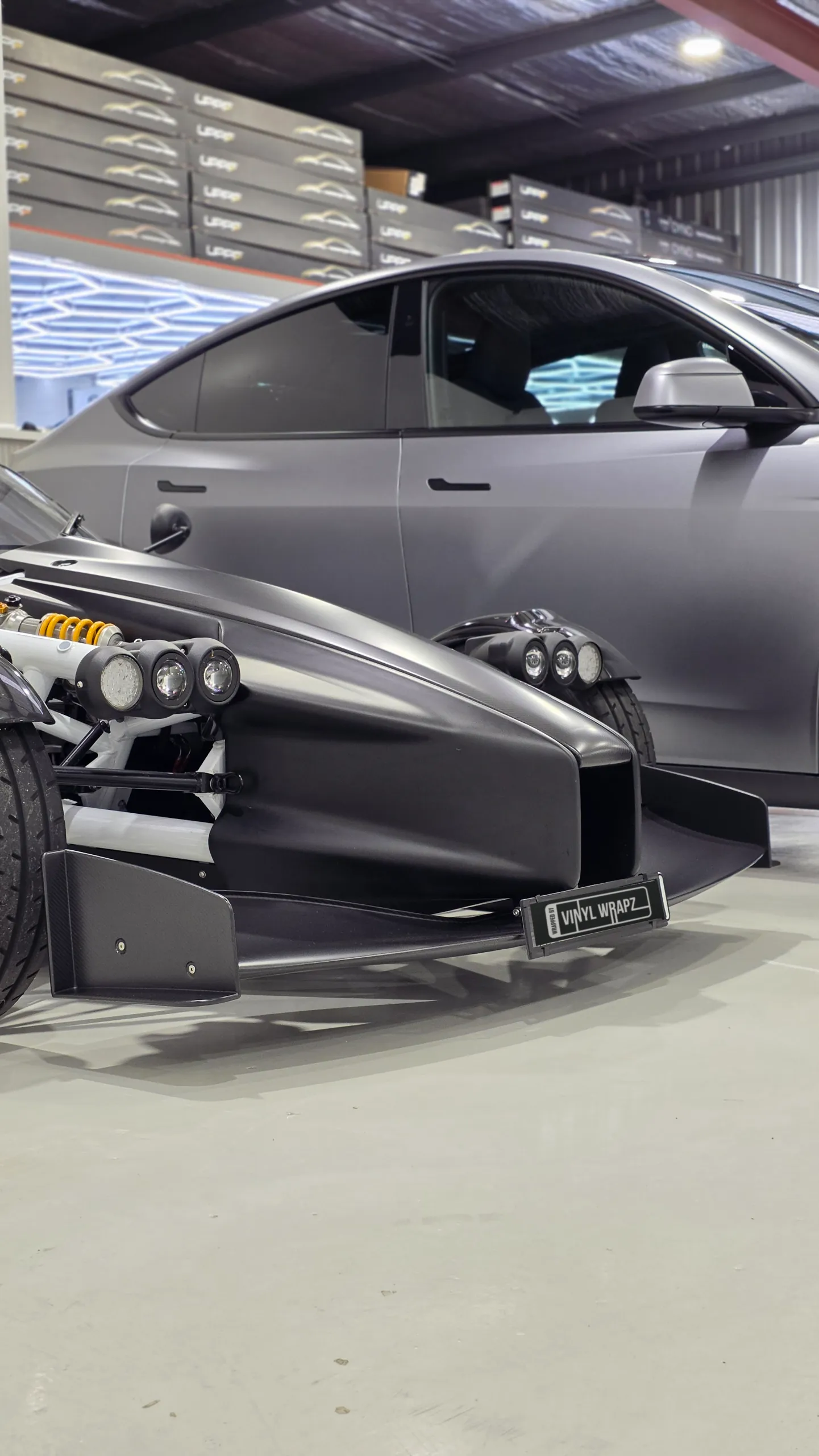 Black Ariel Atom front nose and wing with a grey Tesla behind it