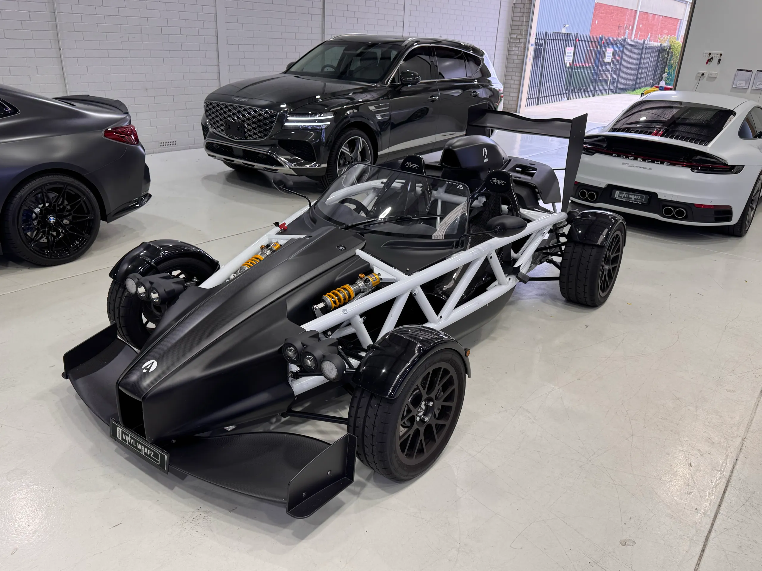 Black Ariel Atom with a white tubular frame and exposed suspension, viewed from the front quarter