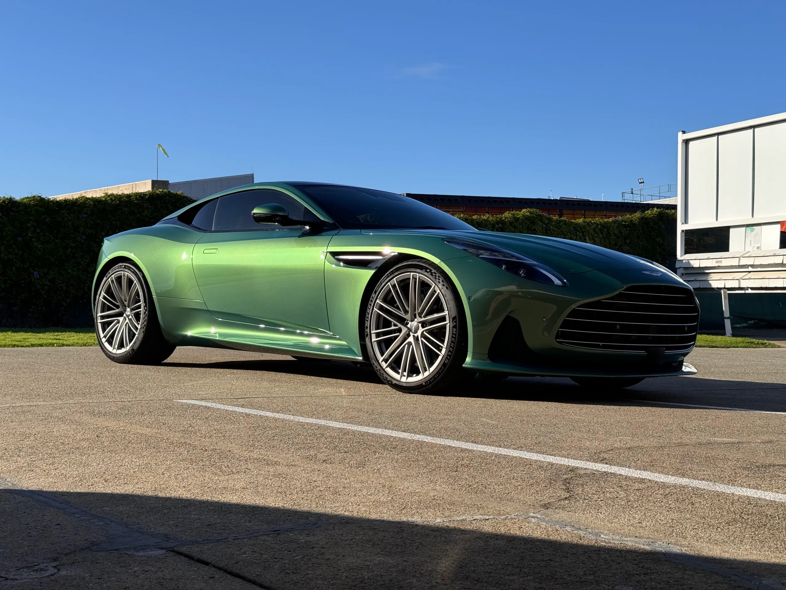 Green Aston Martin DB12 viewed from a low front-quarter angle outdoors