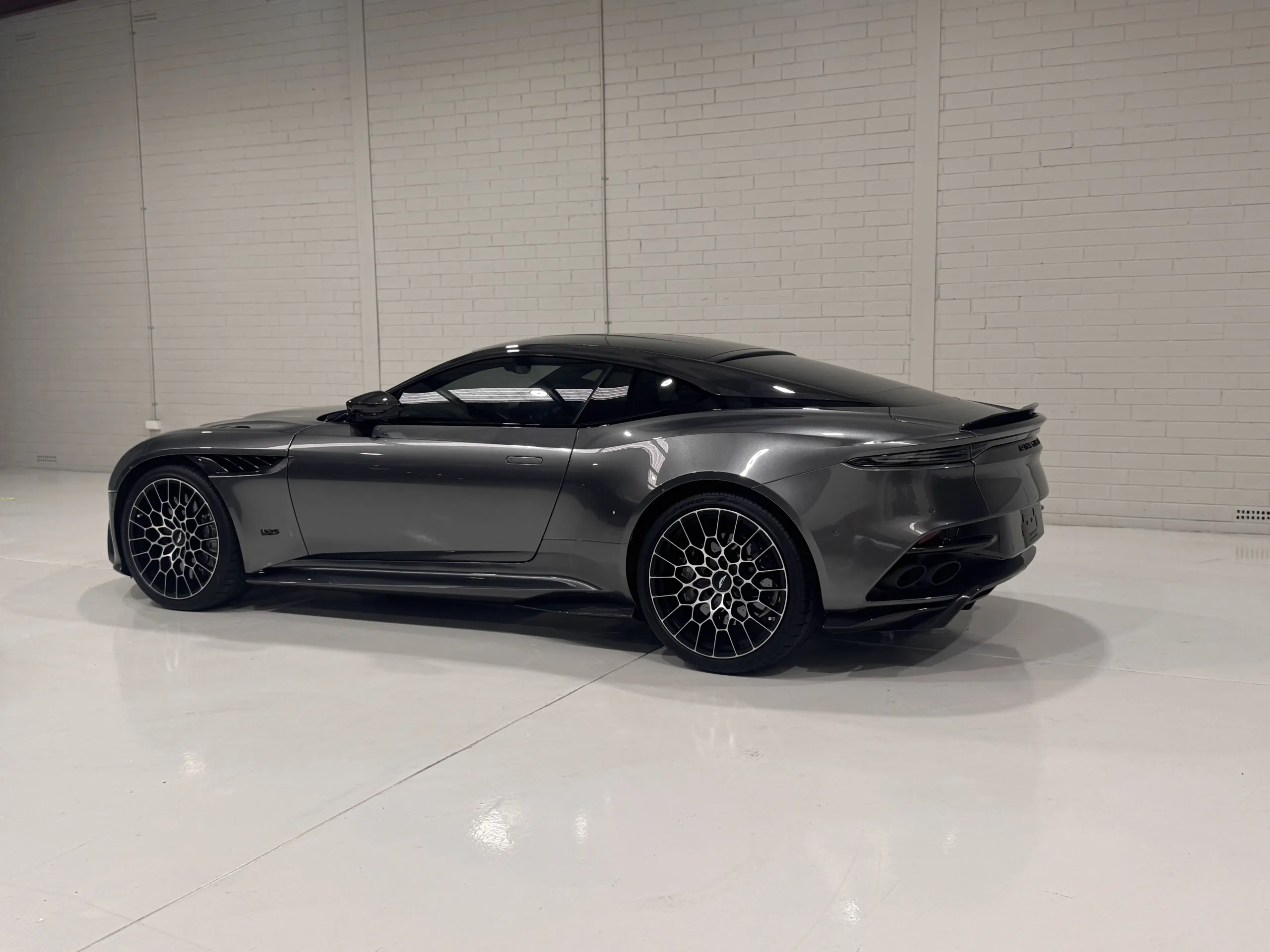 Gloss grey Aston Martin DBS viewed from the side and rear inside the workshop