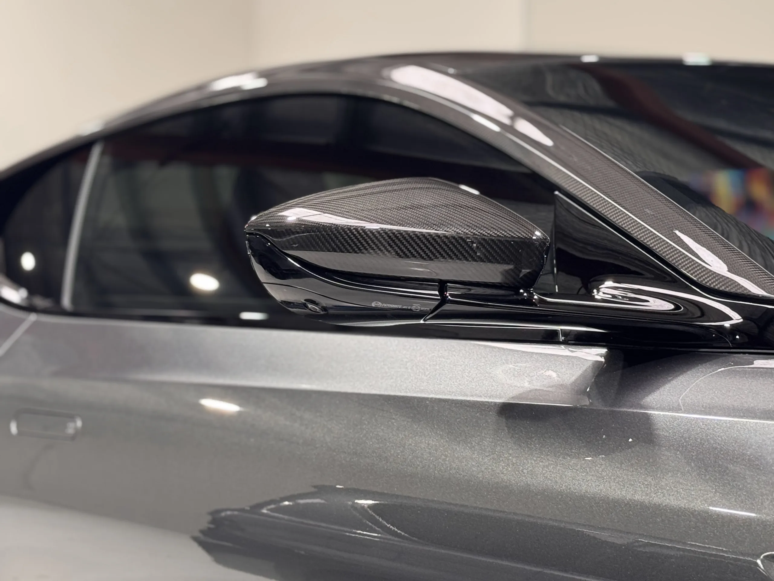 Carbon-fibre mirror cap beside the metallic grey Aston Martin door