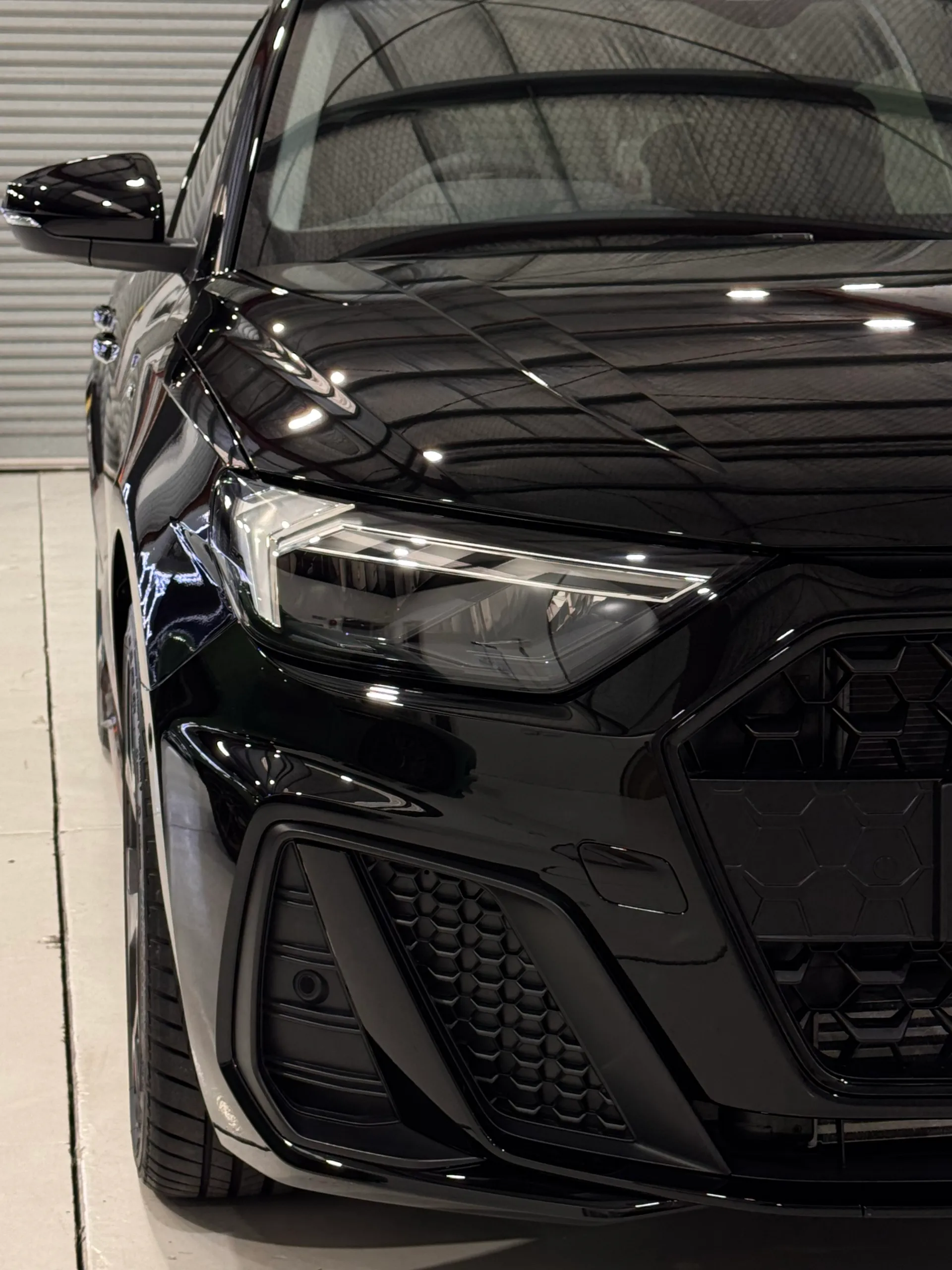 Portrait close-up of the Audi A1 headlight and gloss black front bodywork