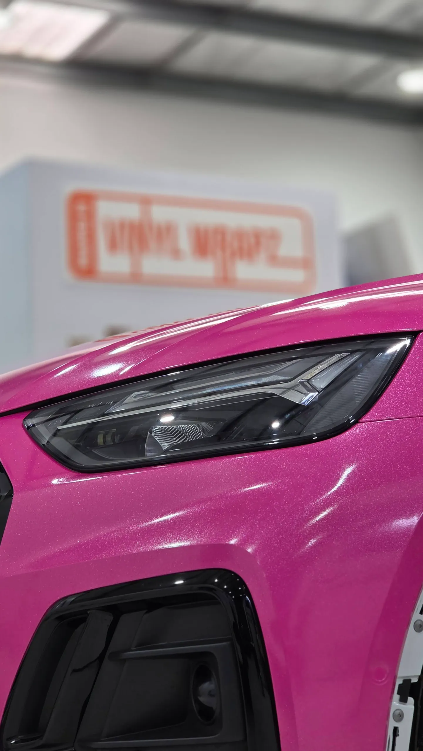 Sparkling pink Audi Q5 Sportback headlight and front bumper during wrapping, with arch trim removed
