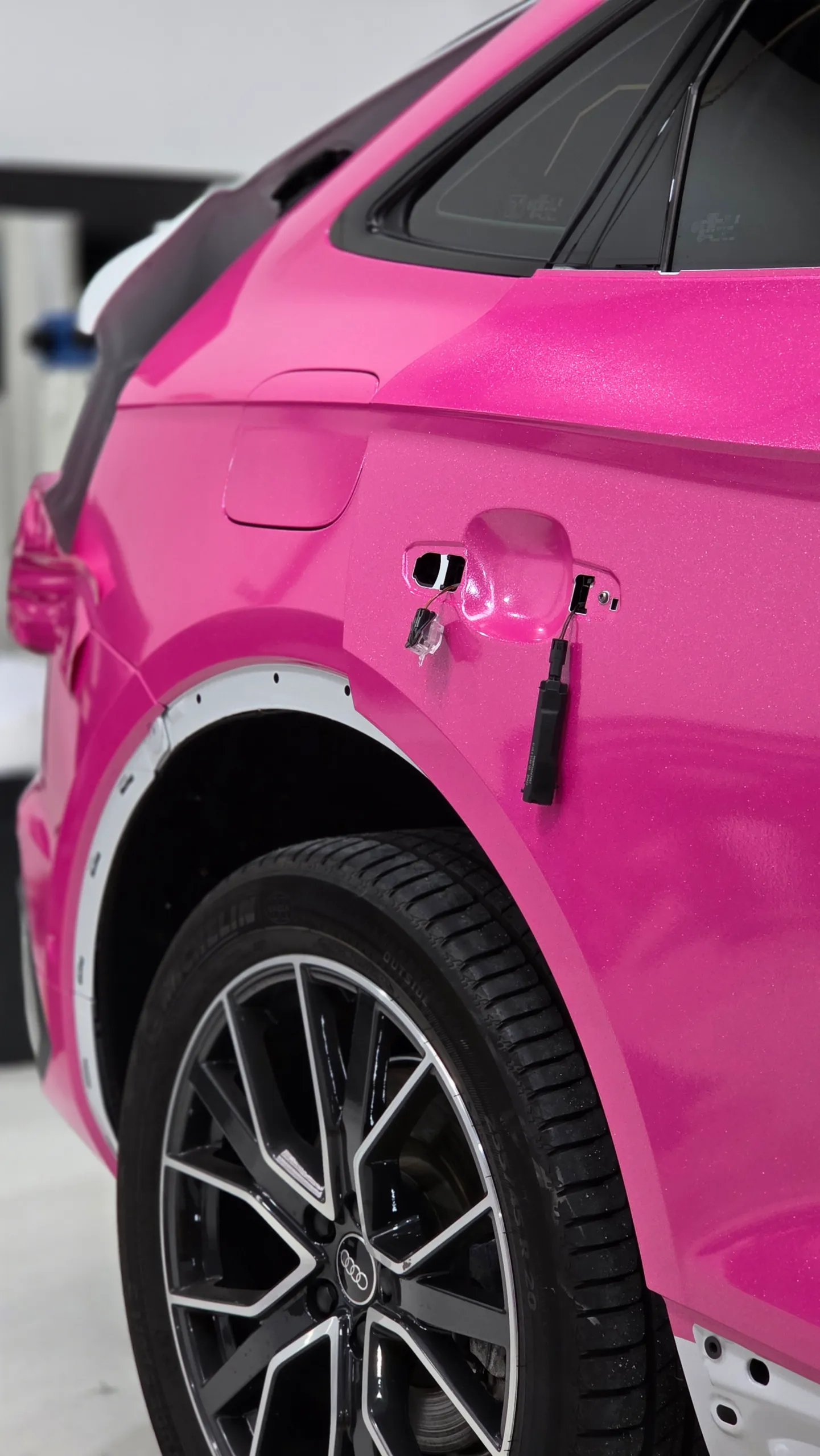 Pink Audi Q5 Sportback rear door and wheel arch during wrapping, with handle and arch trim removed