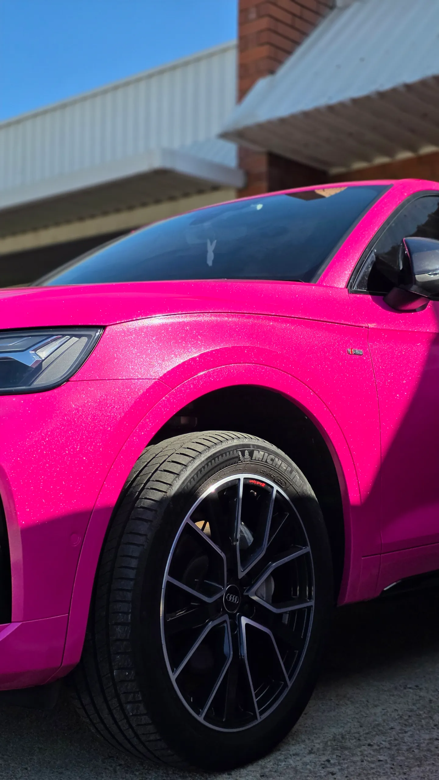 Low front-side detail of the pink Audi Q5 Sportback wheel, guard and door outdoors