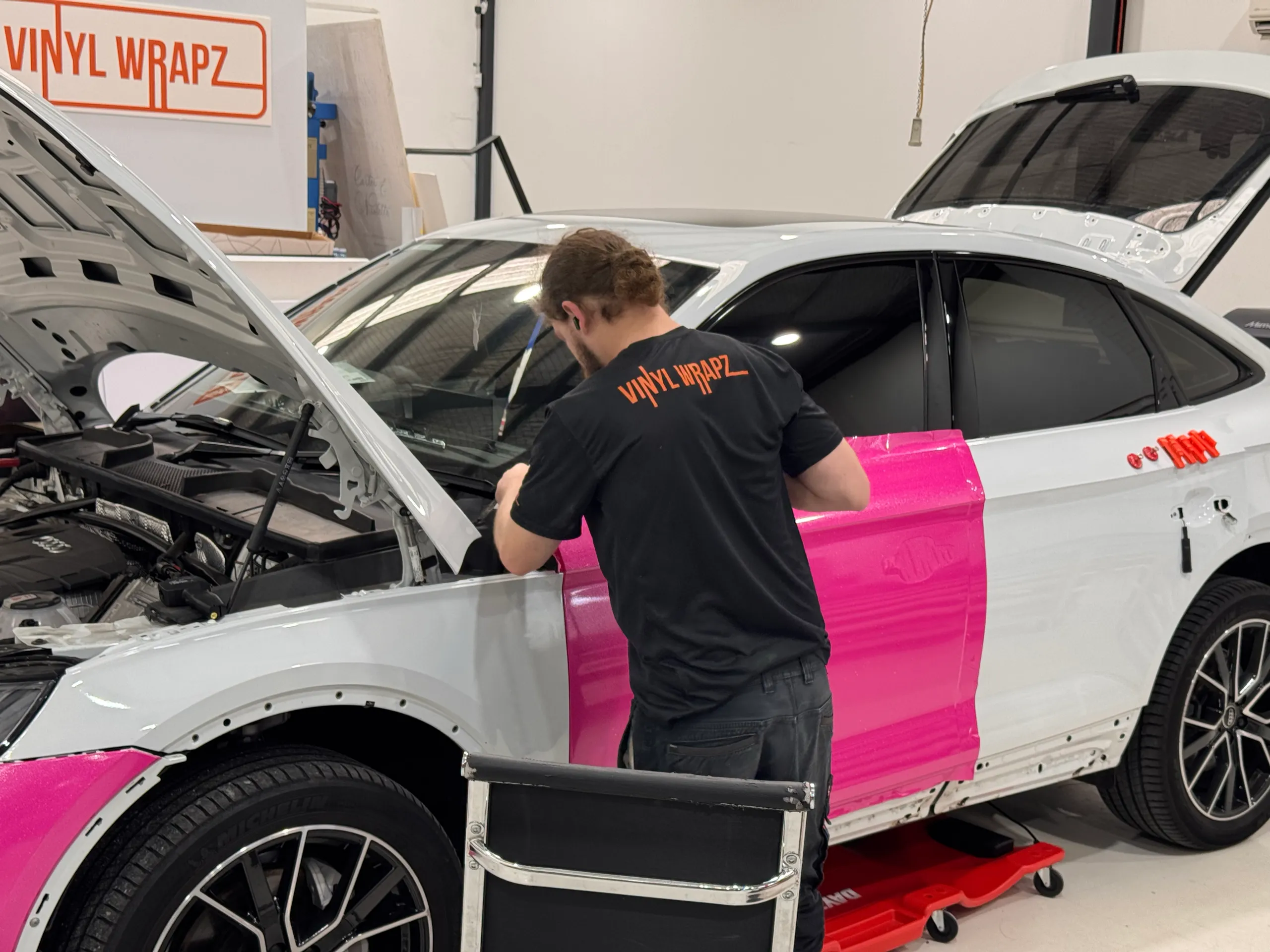 Back-facing installer working beside an Audi Q5 Sportback door during its pink wrap installation