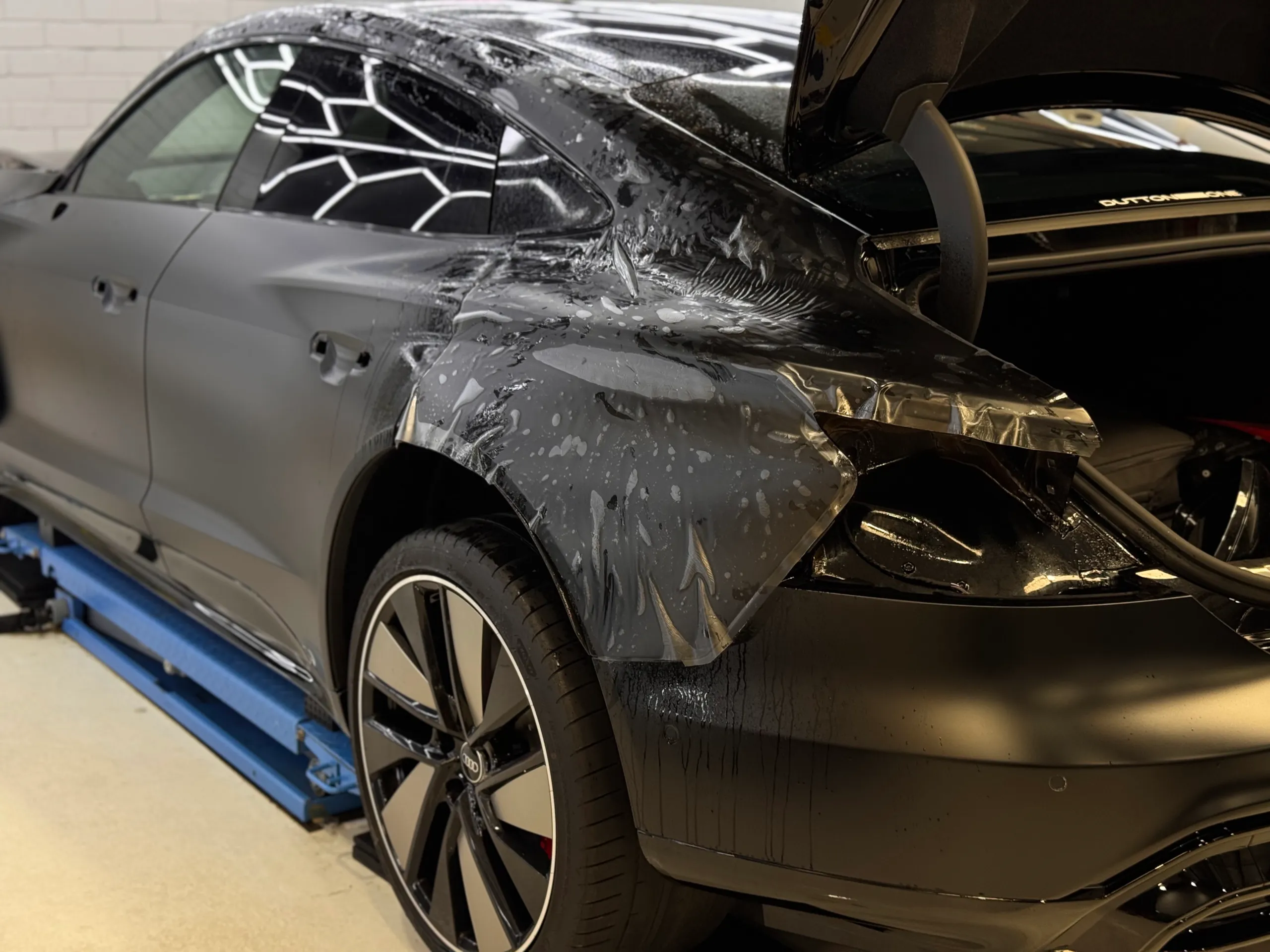 Wet film on the Audi RS e-tron GT rear quarter, with the boot open and door handles removed