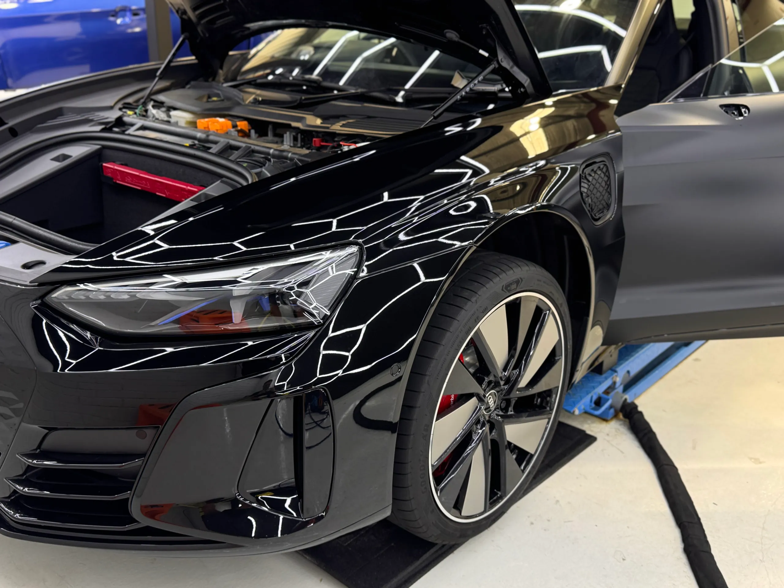 Audi RS e-tron GT with bonnet and door open during film installation in the workshop