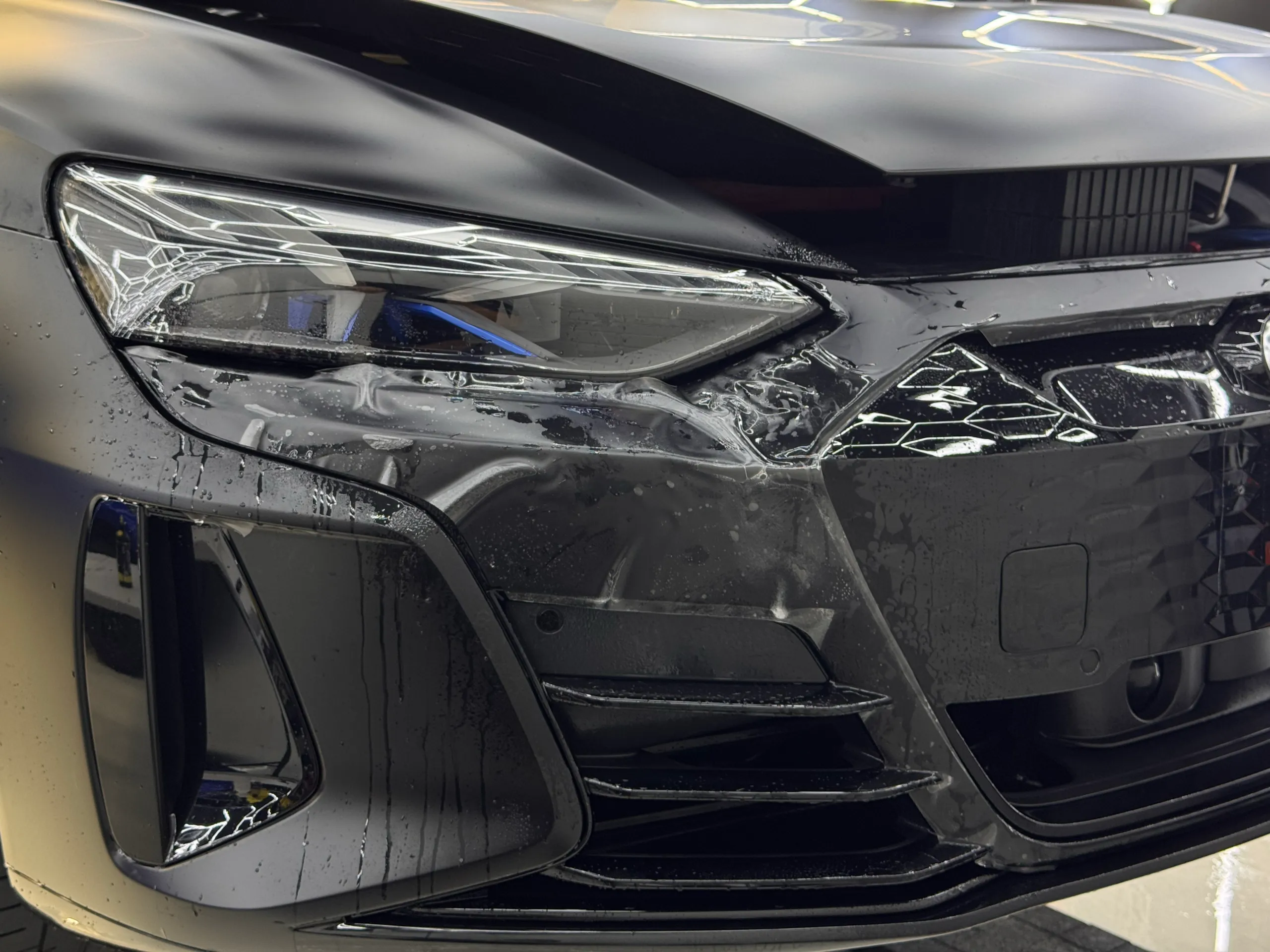 Wet film around the Audi RS e-tron GT front headlight and bumper during installation