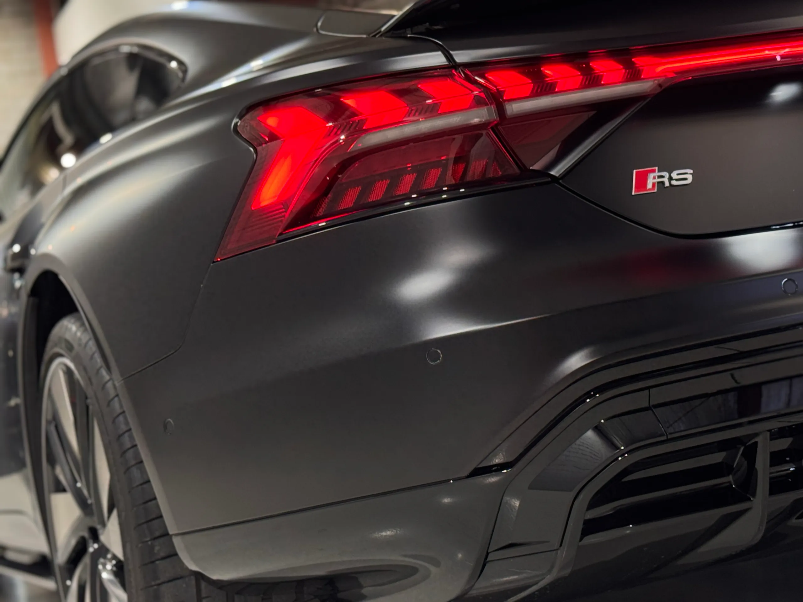 RS badge beside the illuminated rear light on the matte black Audi e-tron GT