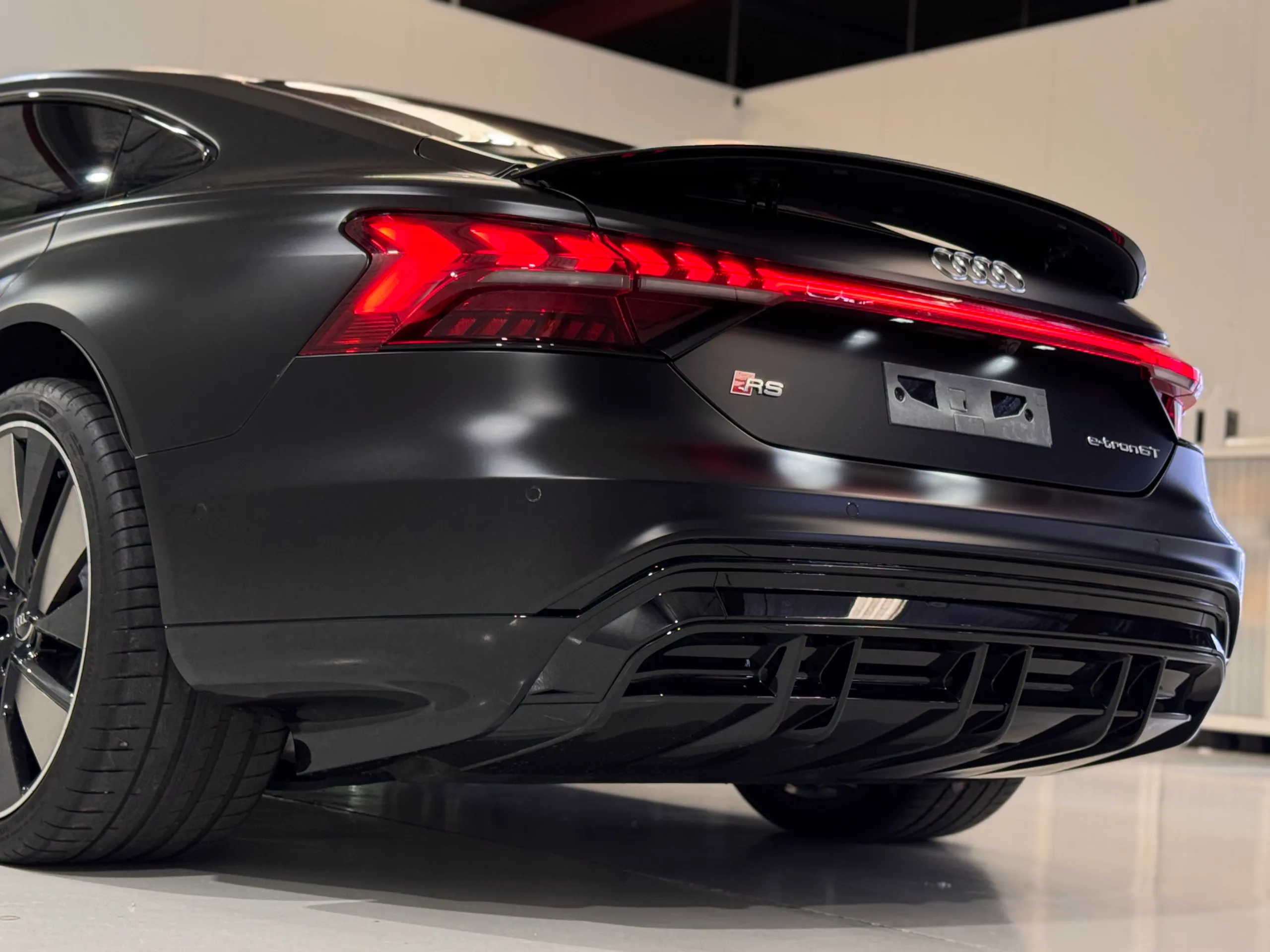 Low rear-quarter view of the matte black Audi RS e-tron GT diffuser and rear light bar