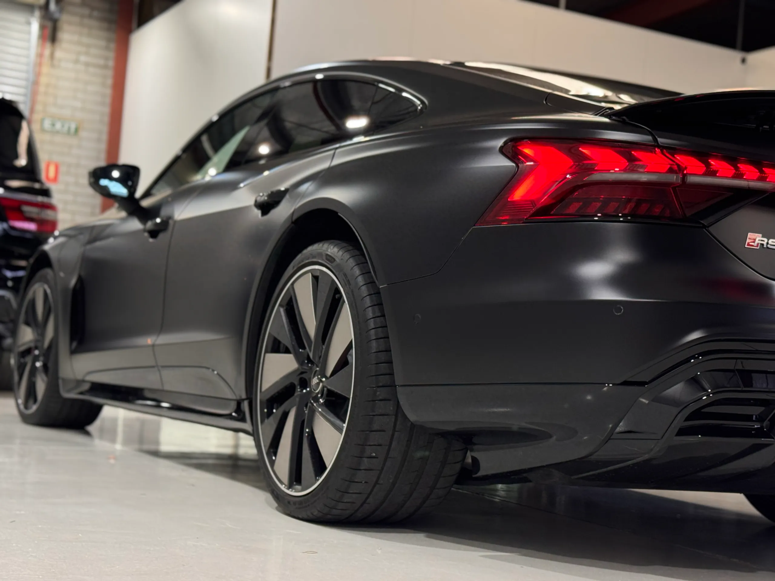 Low view along the matte black Audi RS e-tron GT body towards the rear wheel