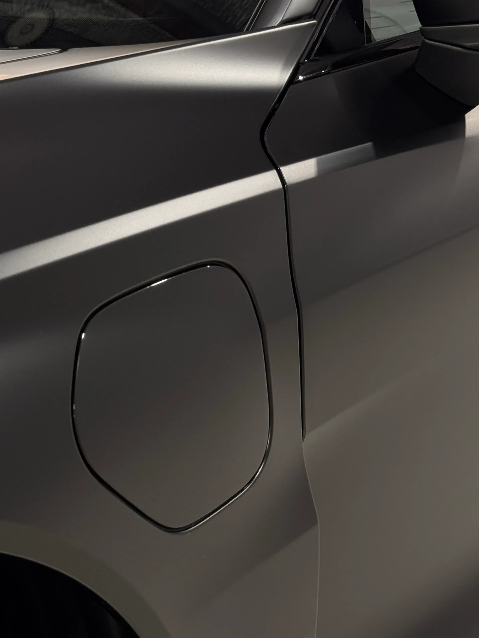 Close-up of the charging-port flap on the matte black Audi RS e-tron GT front guard