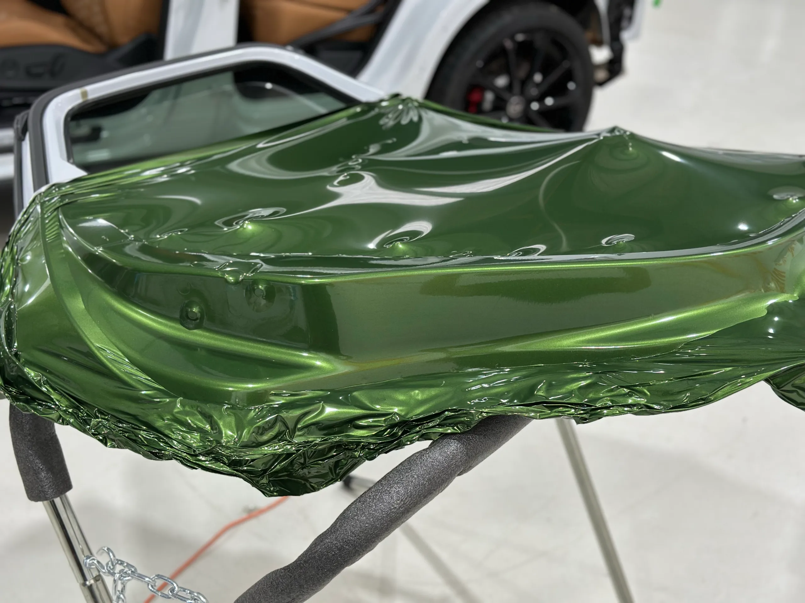 Metallic green film being fitted around the inner edge of a removed Audi door on a stand