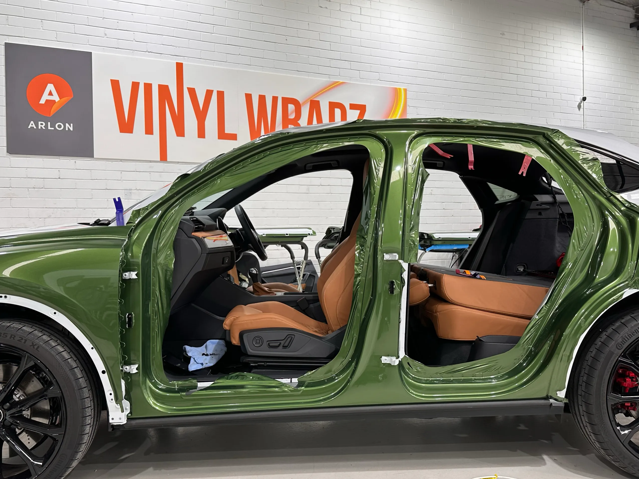 Green-wrapped door openings on an Audi RS Q3 Sportback with its doors removed, exposing the tan interior