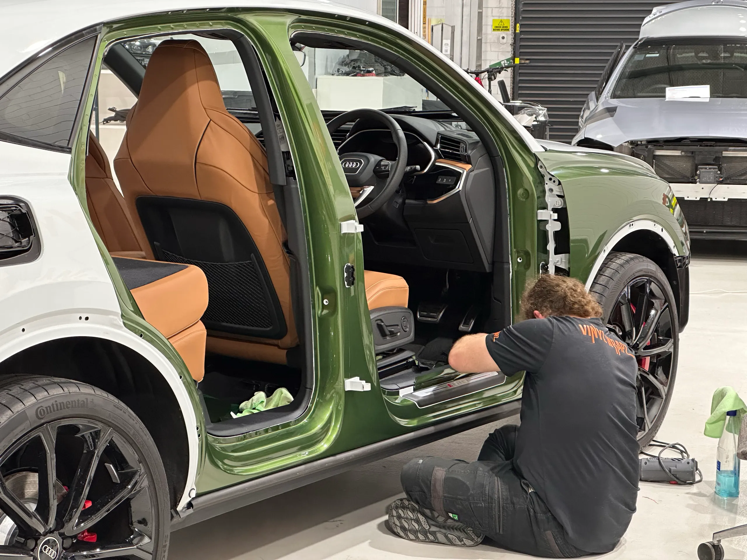 Installer fitting metallic green wrap inside the Audi RS Q3 Sportback door opening, with the doors removed