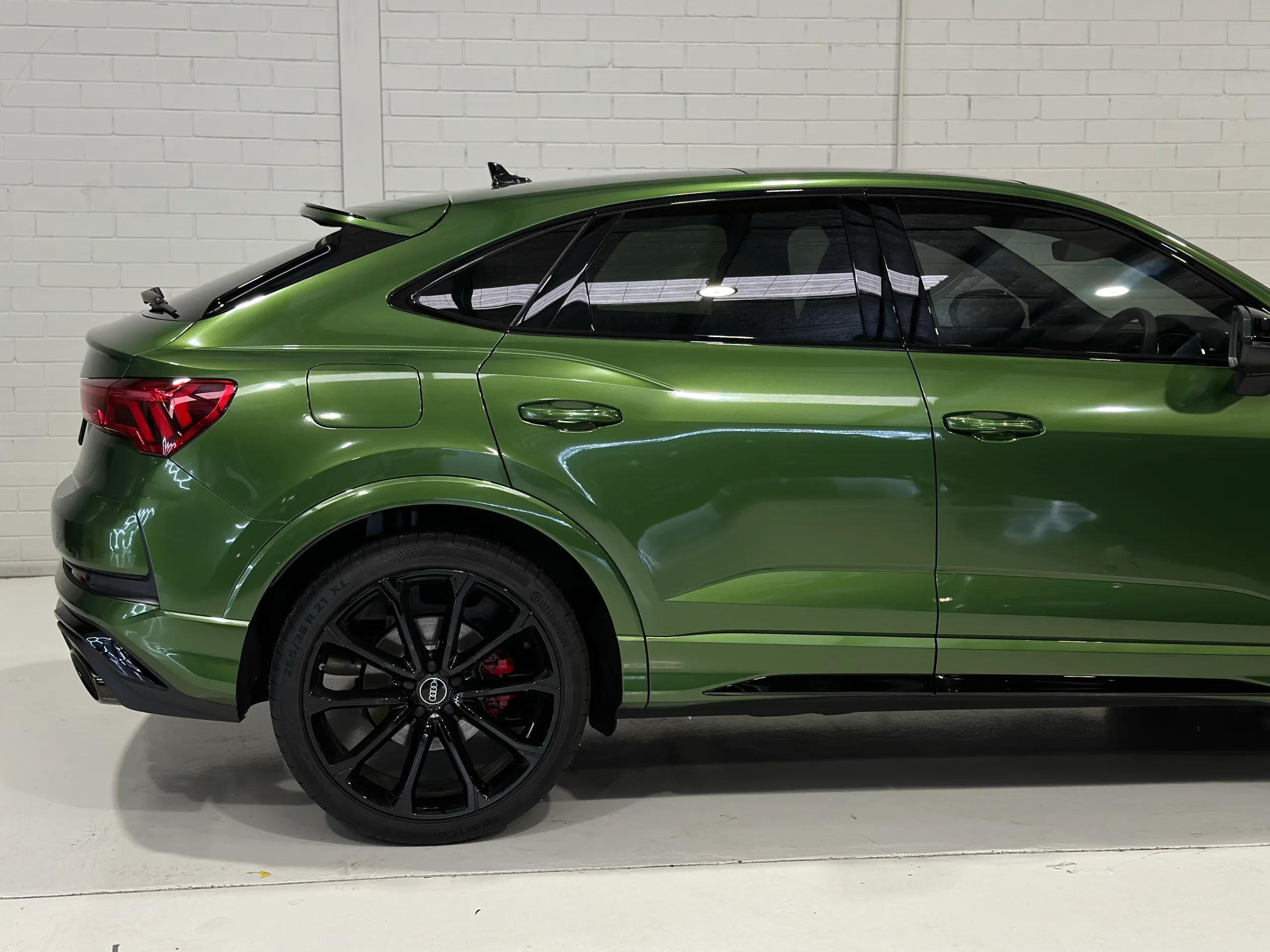 Side detail of a green Audi RS Q3 Sportback, showing the rear wheel, doors and sloping roofline
