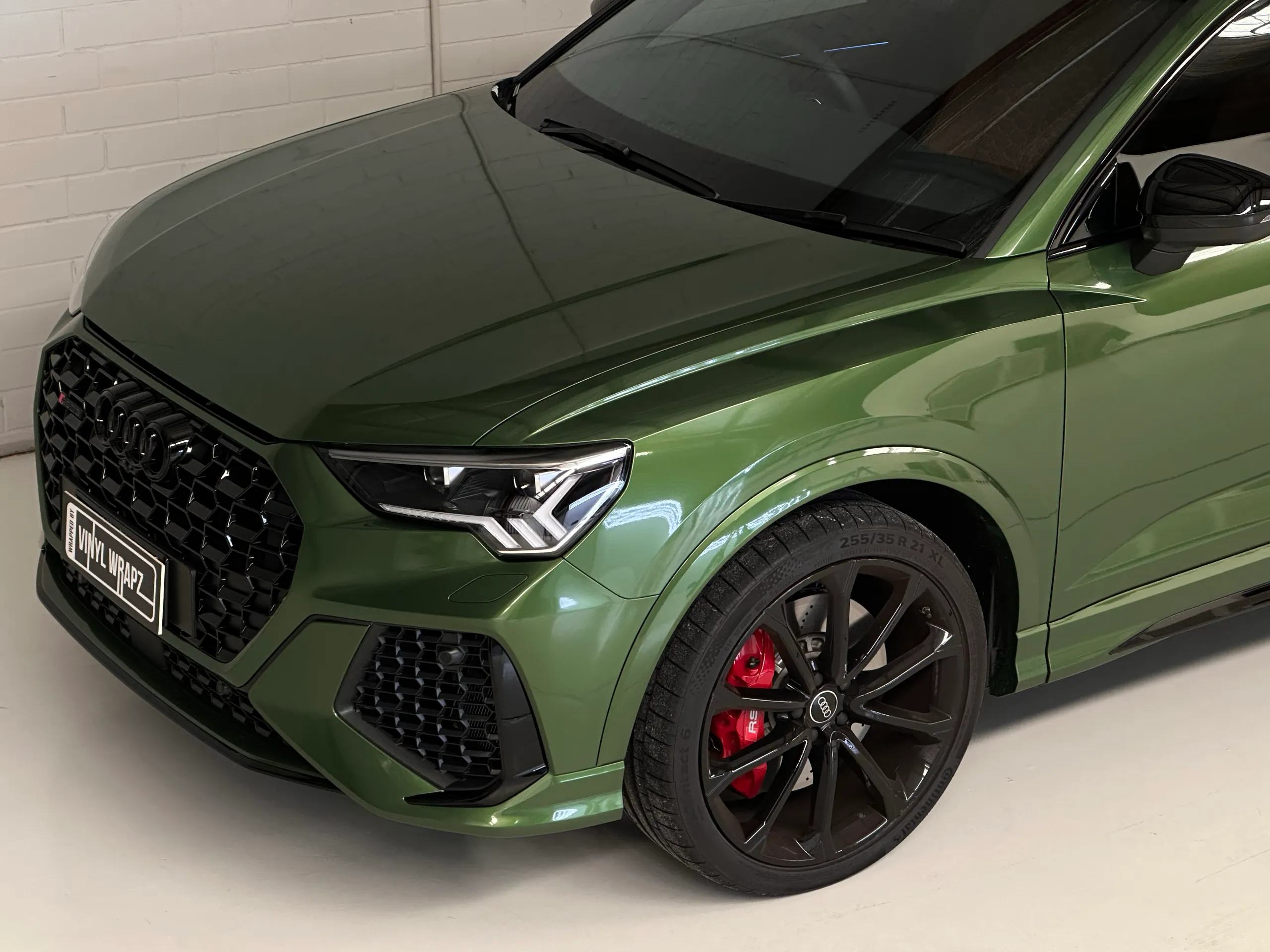 Elevated front-quarter detail of a green Audi RS Q3 Sportback bonnet, wheel and headlight