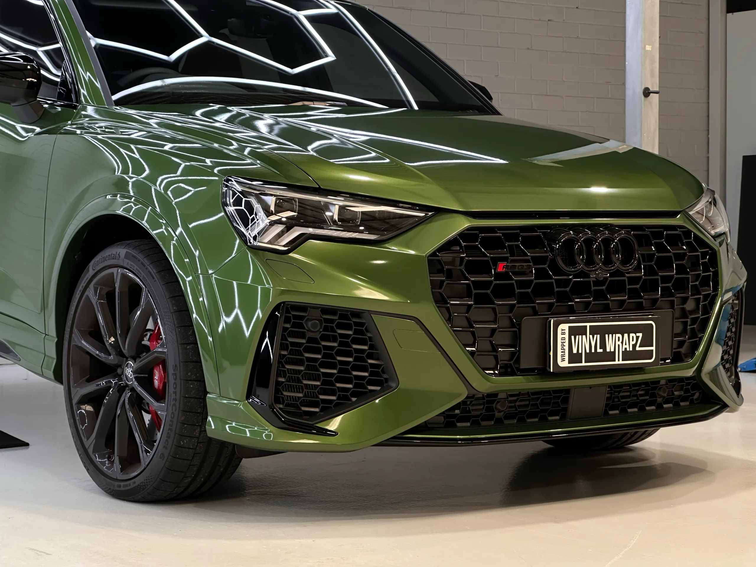Green Audi RS Q3 Sportback front quarter reflecting hexagonal workshop lights
