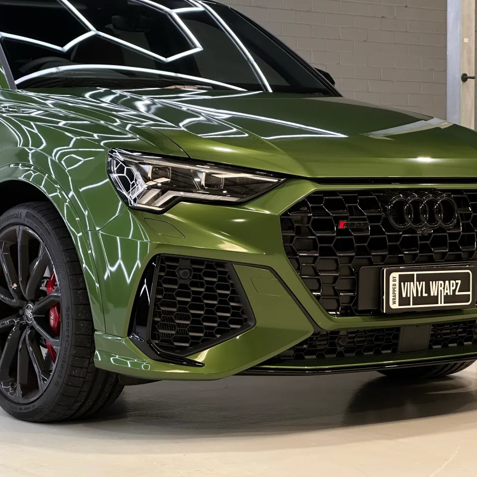Green Audi RS Q3 Sportback front quarter reflecting hexagonal workshop lights