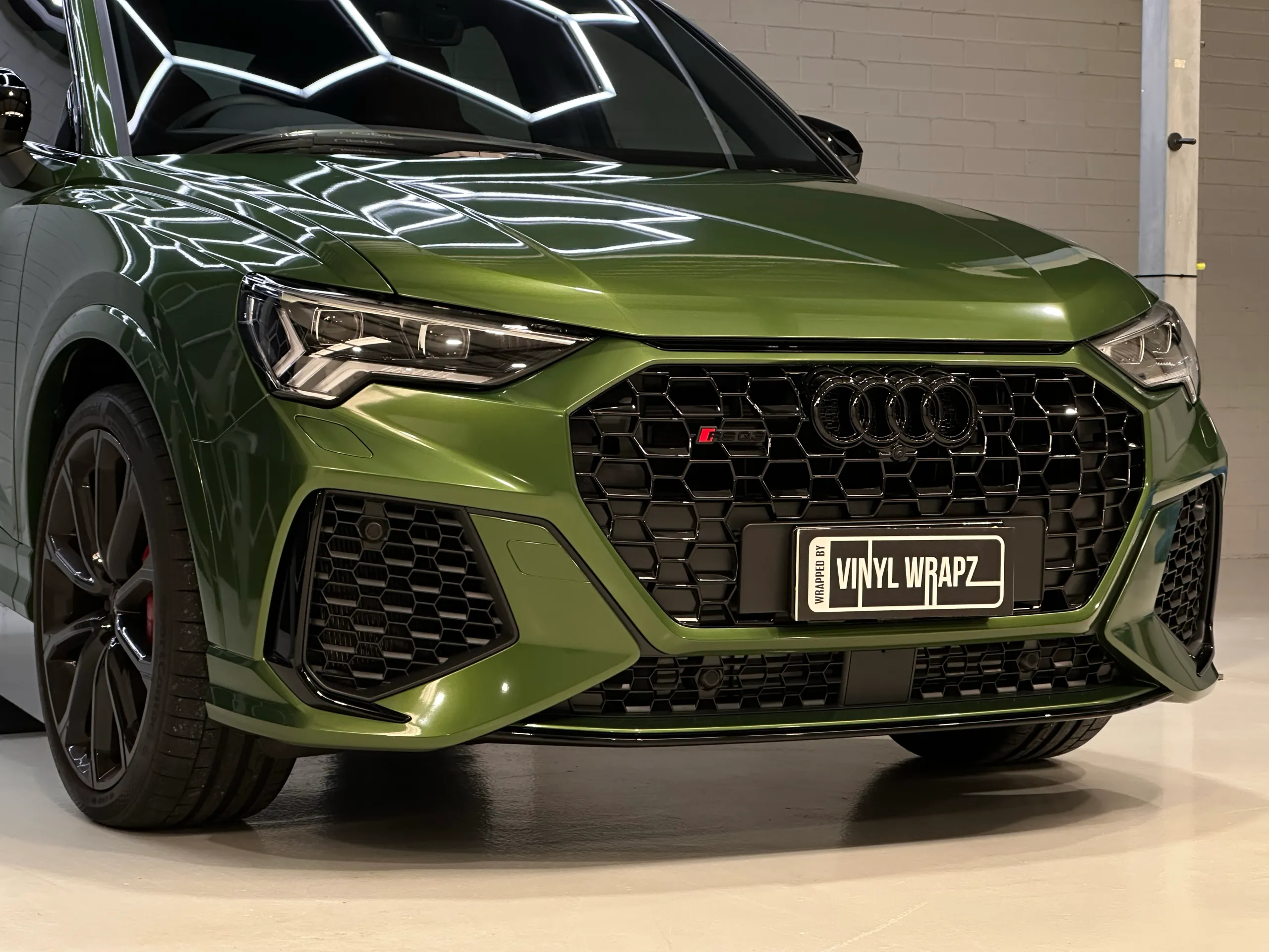 Low front detail of a green Audi RS Q3 Sportback, showing its honeycomb grille and bumper