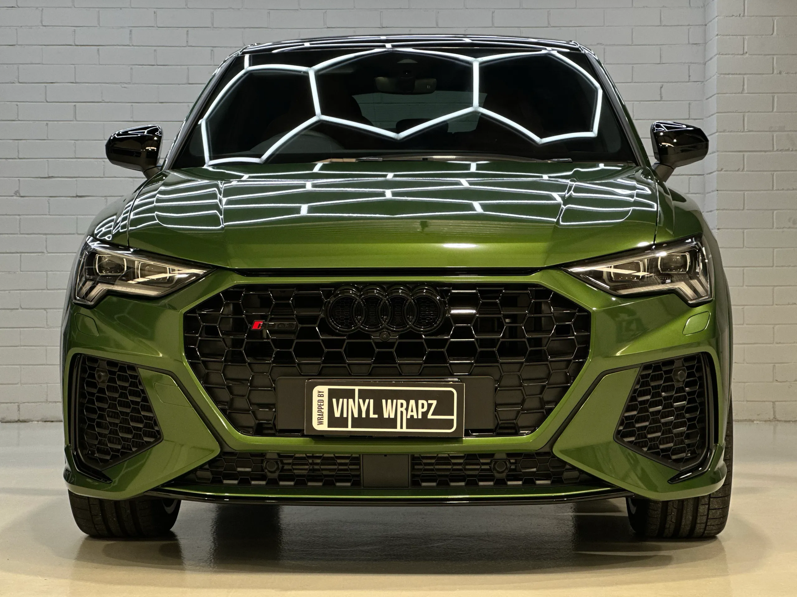 Front view of a metallic green Audi RS Q3 Sportback, with black grille and mirrors