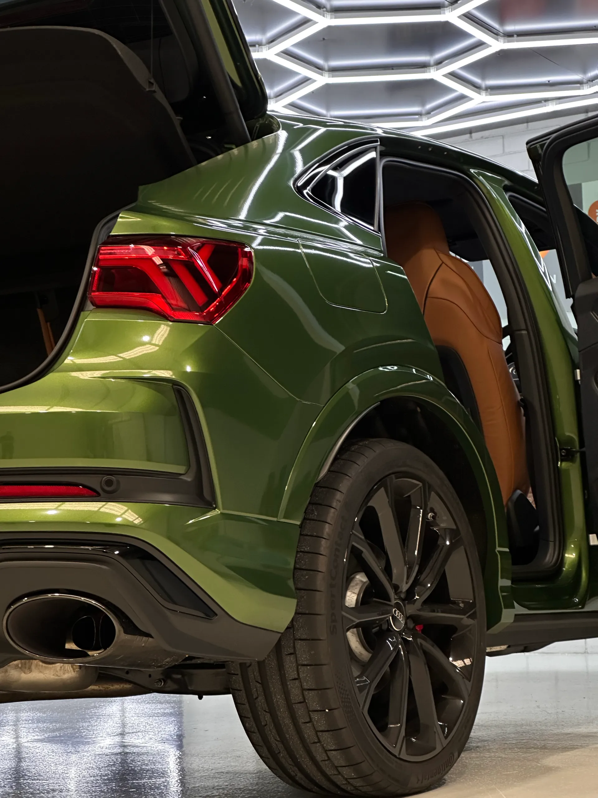 Green Audi RS Q3 Sportback rear quarter with the tailgate and rear door open, showing green door edges