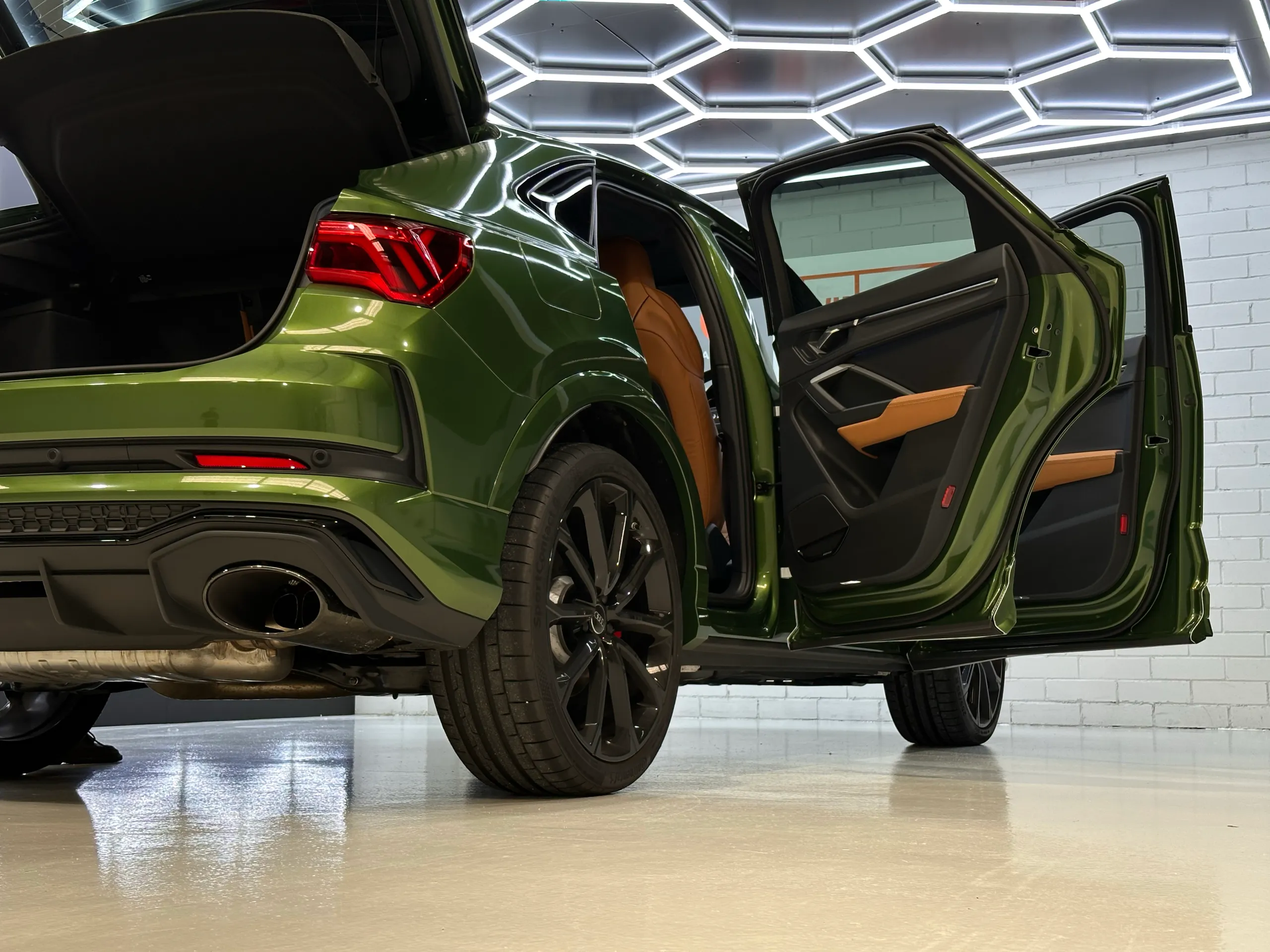 Rear quarter of a green Audi RS Q3 Sportback with its doors and tailgate open, exposing the tan interior