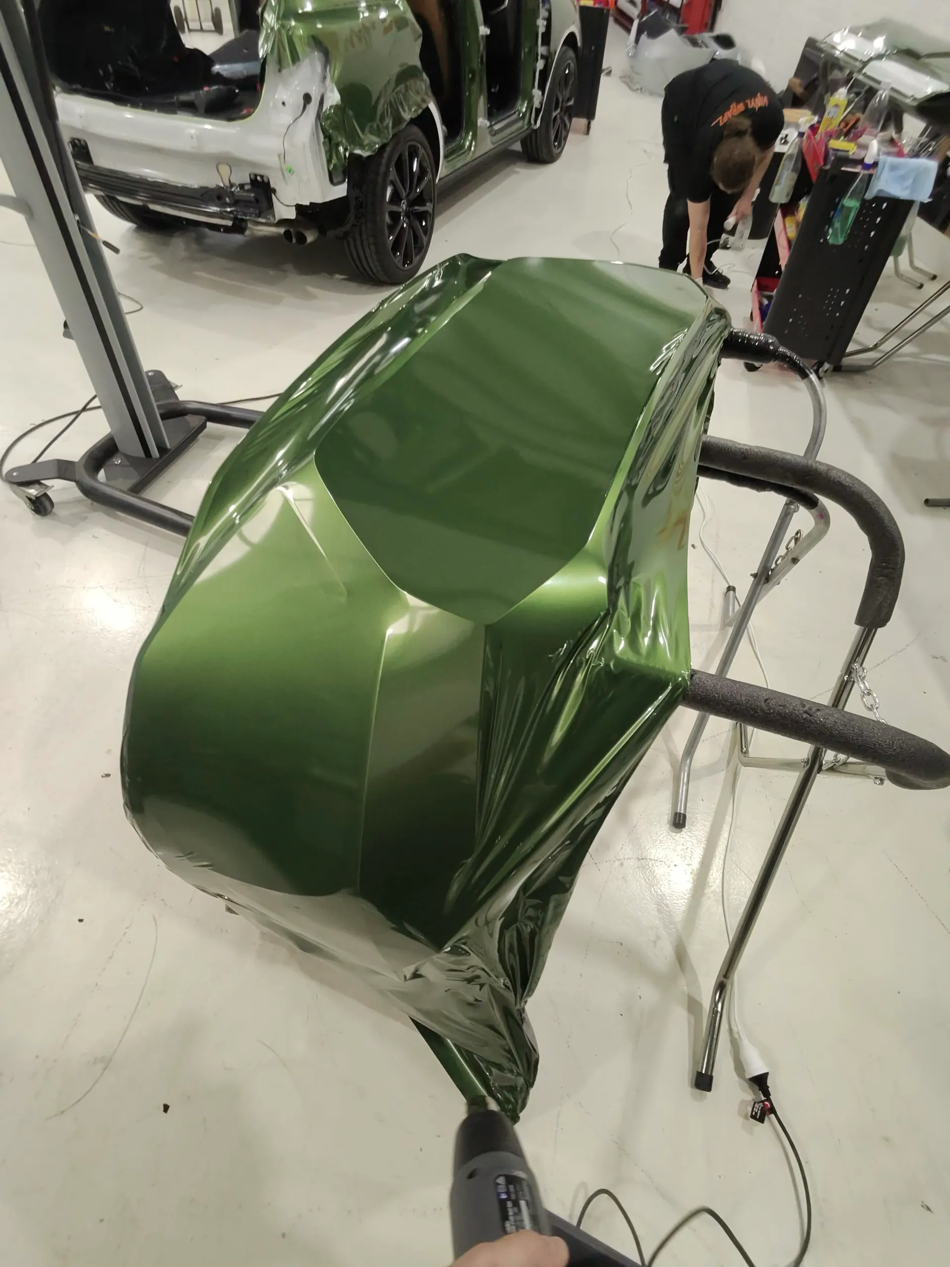 Green film being heated over a removed Audi door on a padded stand