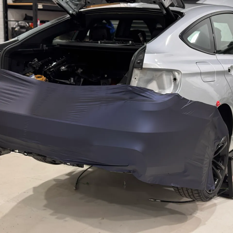 Blue-grey film partly fitted across the BMW Gran Turismo rear bumper during wrapping