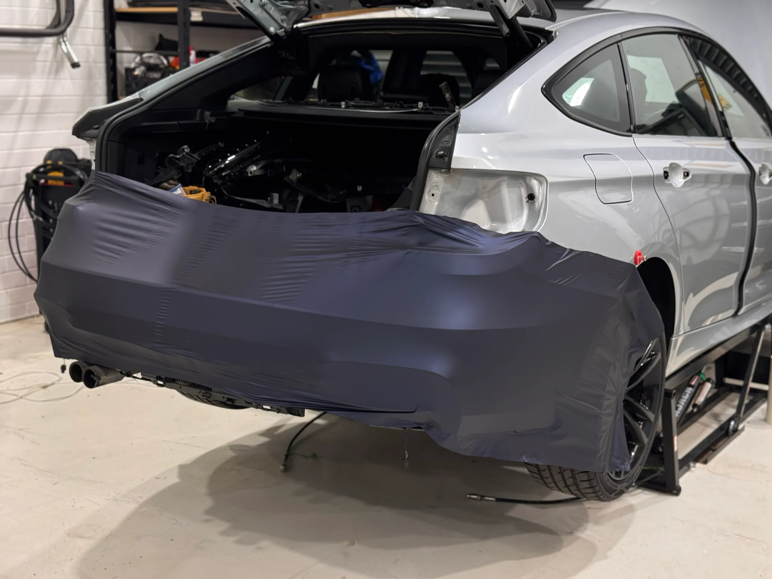 Blue-grey film partly fitted across the BMW Gran Turismo rear bumper during wrapping